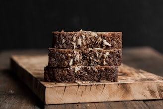 Three slices of dark bread stacked on a wooden board