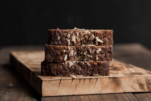 Three slices of dark bread stacked on a wooden board
