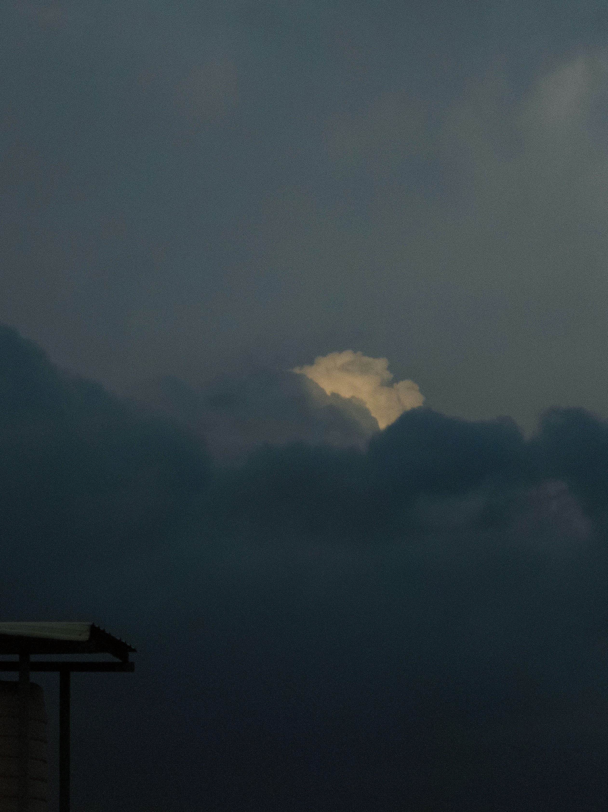 Dark stormy clouds with a single illuminated cloud.