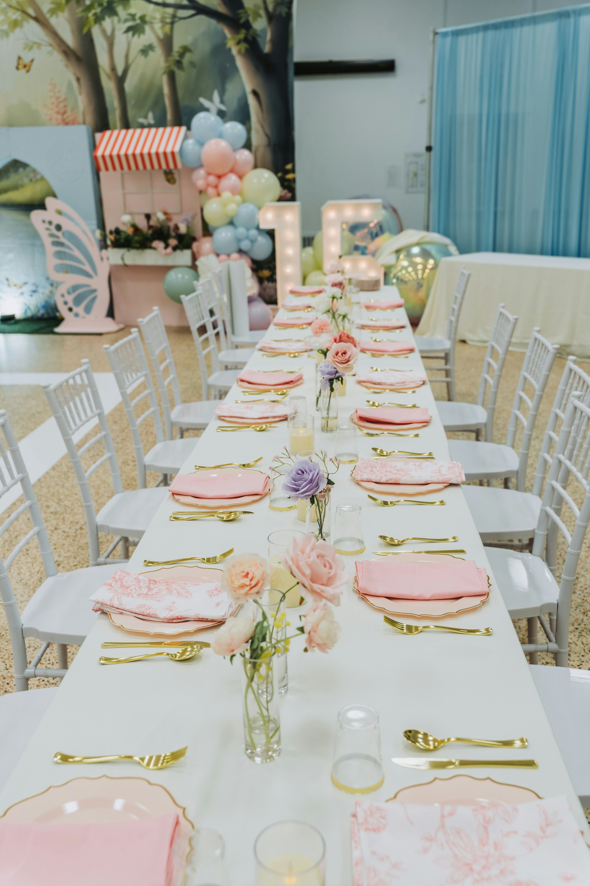 A long table set for a party with pink decorations.