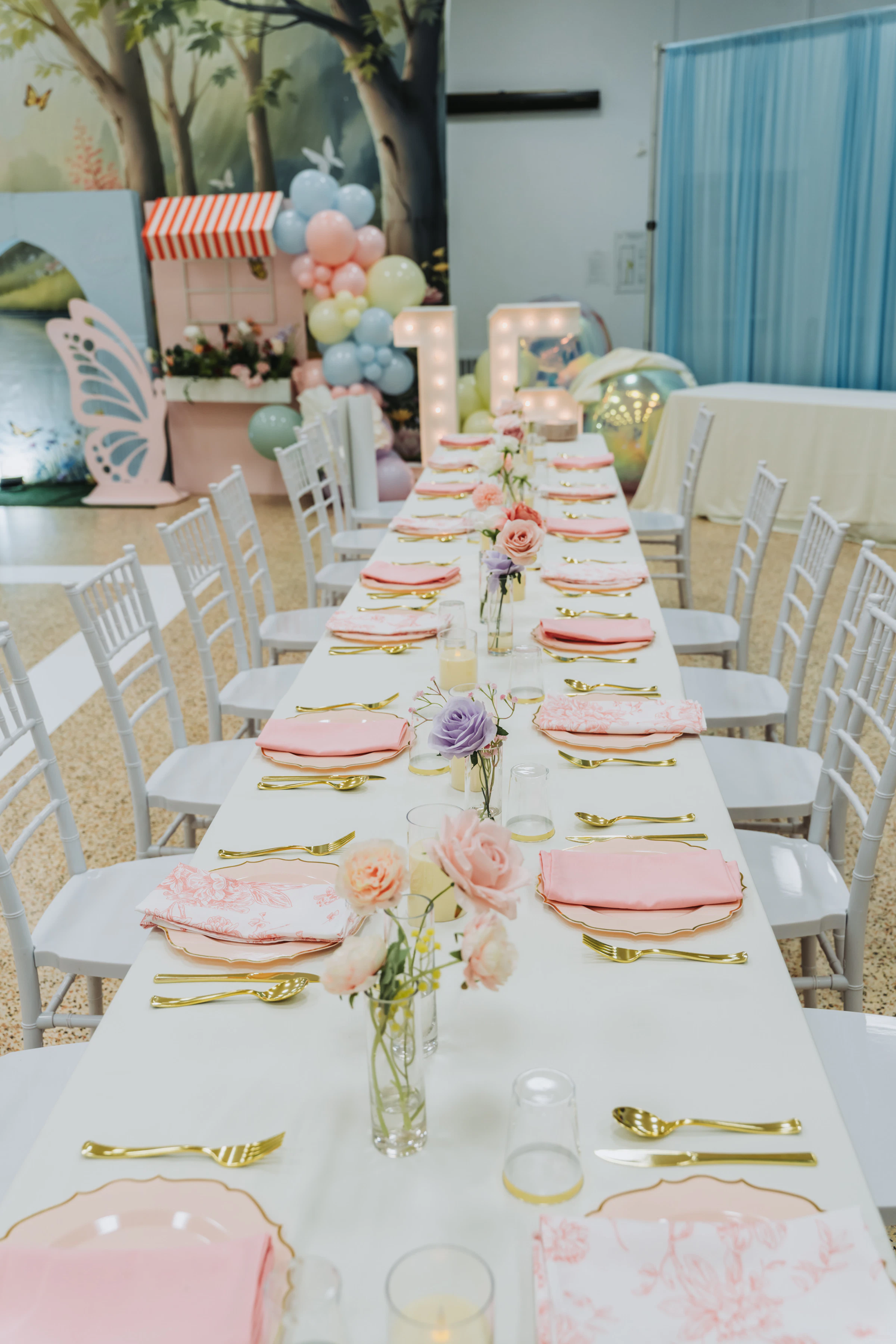 A celebration table arranged with balloons, flowers, tableware, and party decorations