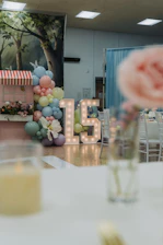 Illuminated number 15 with balloons at a party.