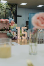 Illuminated number 15 with balloons at a party.