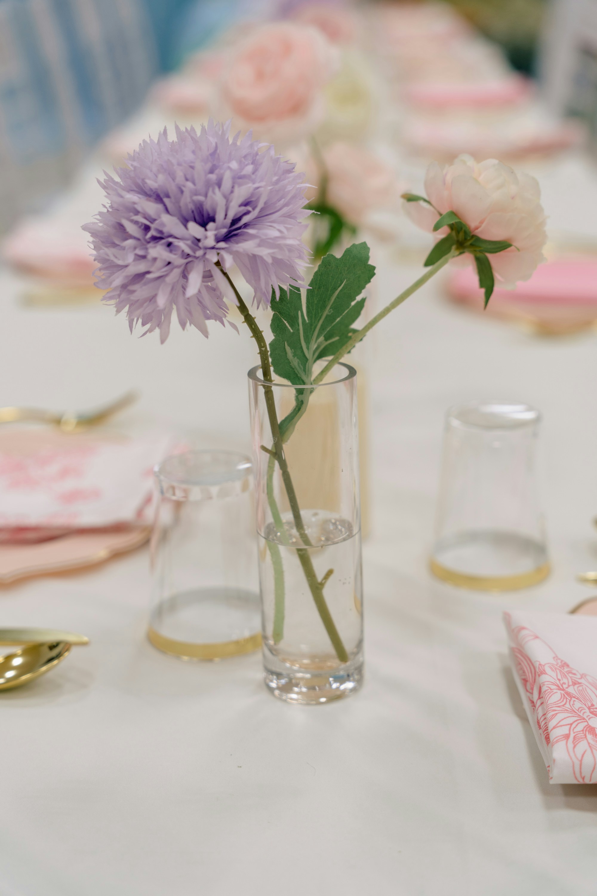 A vase with flowers on a table setting.