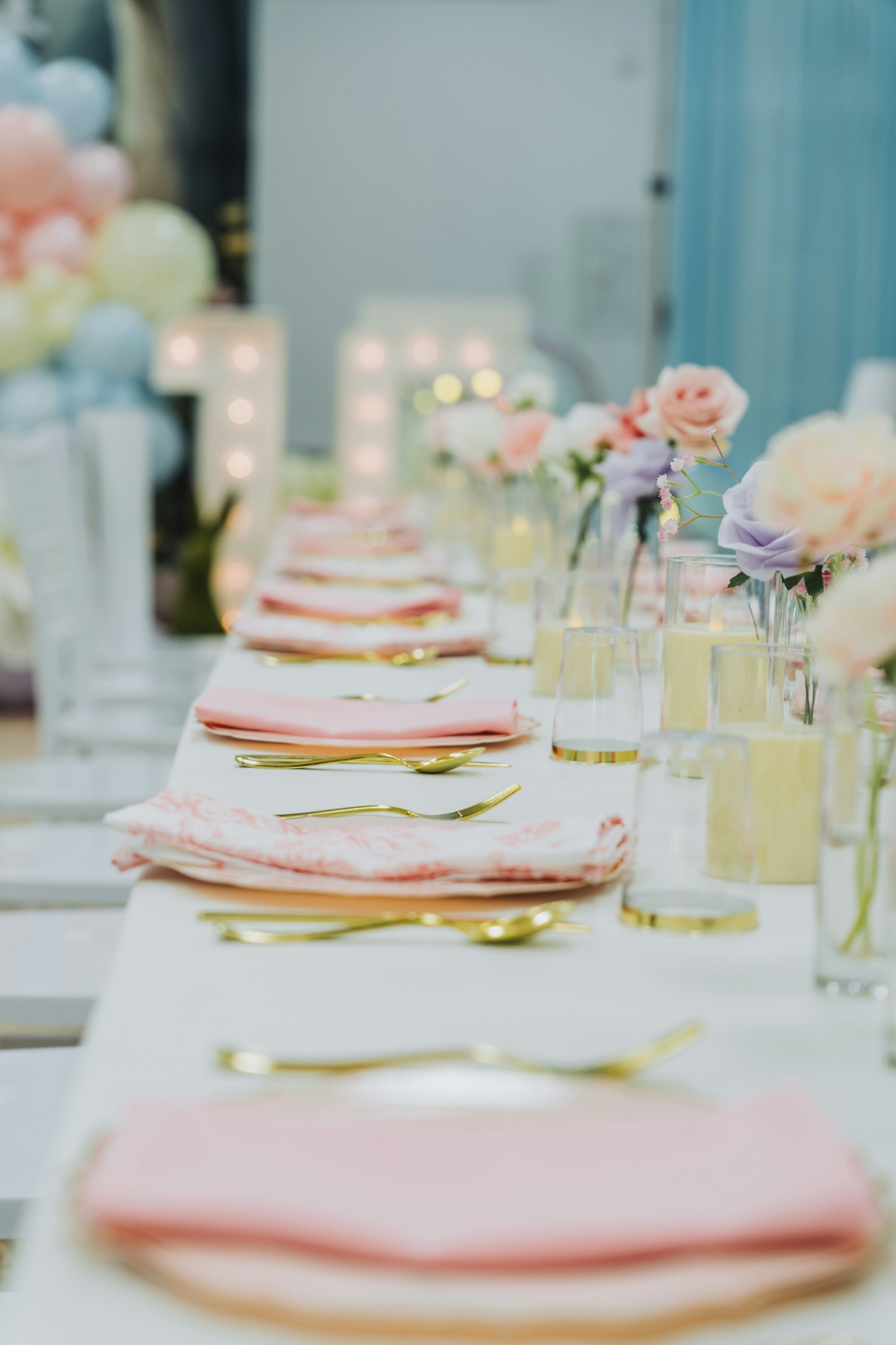 A beautifully set table with pink napkins and gold cutlery.