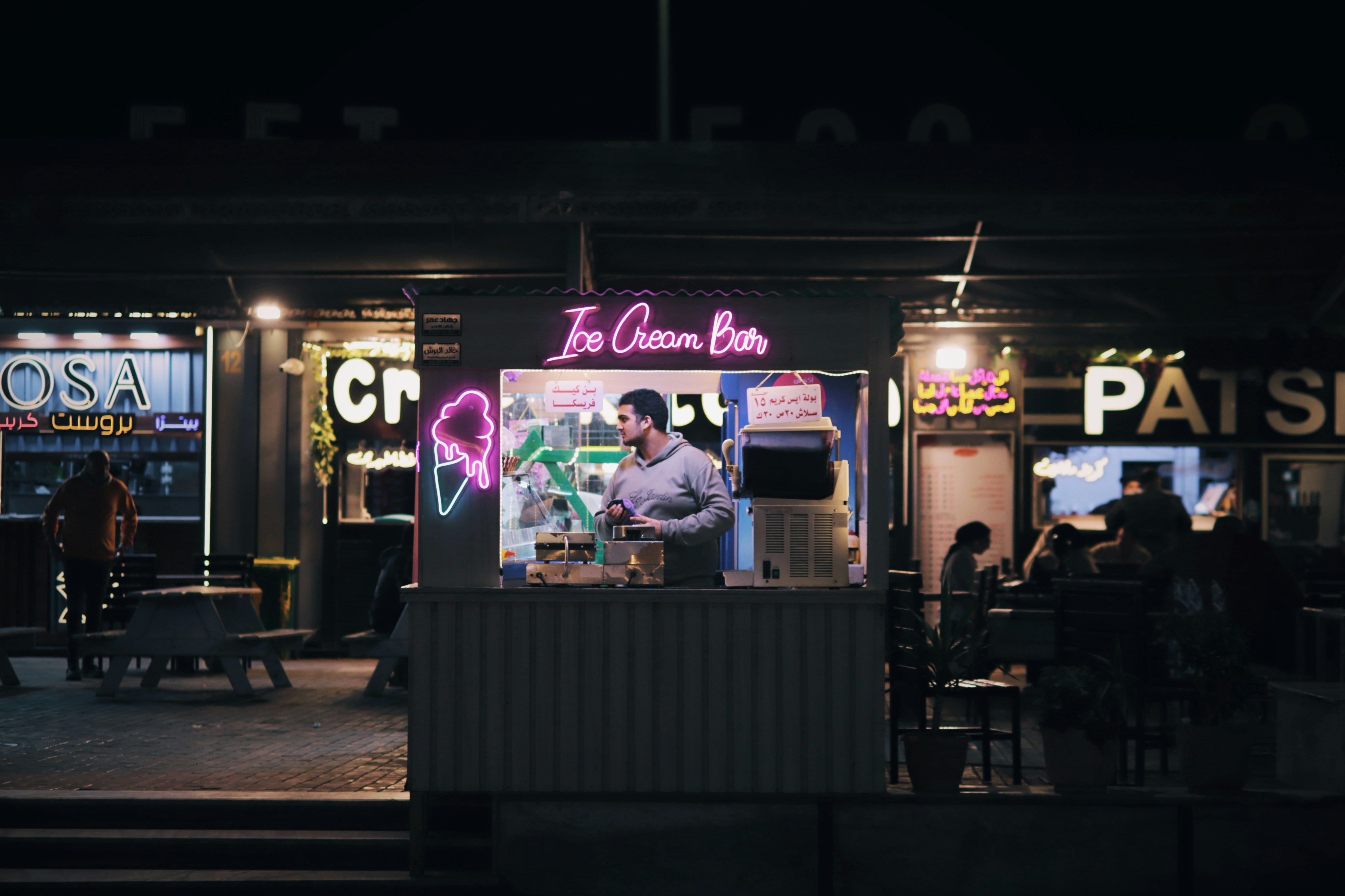 Man working at neon lit ice cream bar at night
