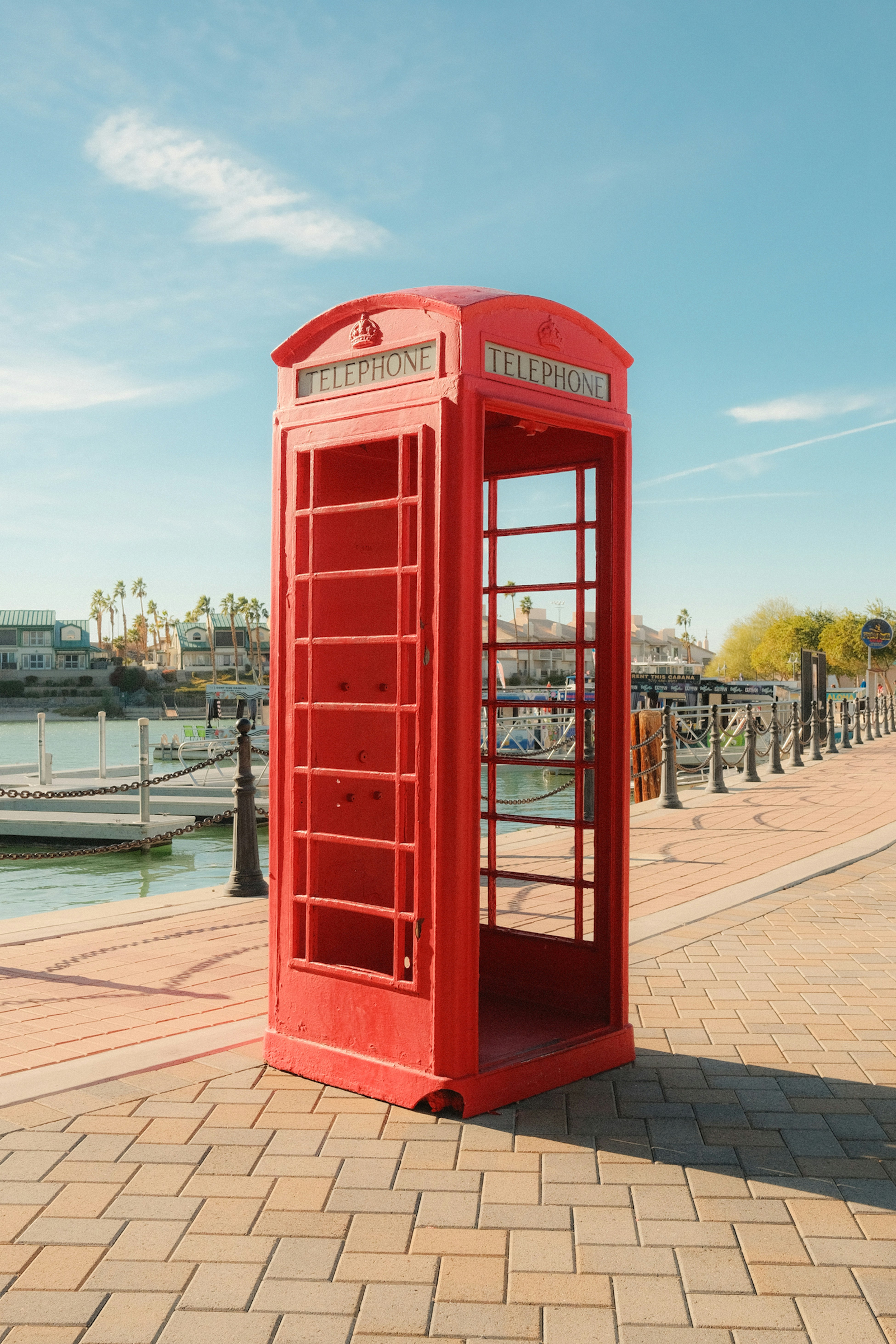 Eine rote Telefonzelle steht an einer Uferpromenade.