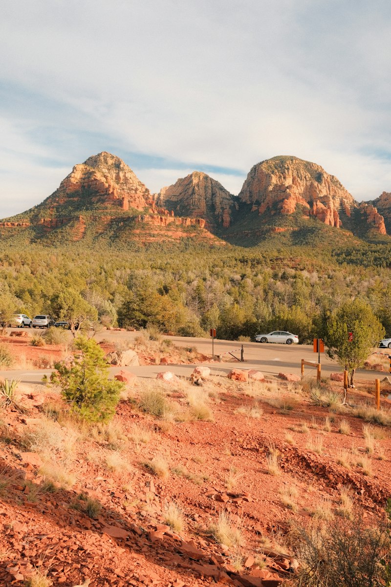 Red rock formations with green trees and cars on a scenic drive in Sedona Arizona