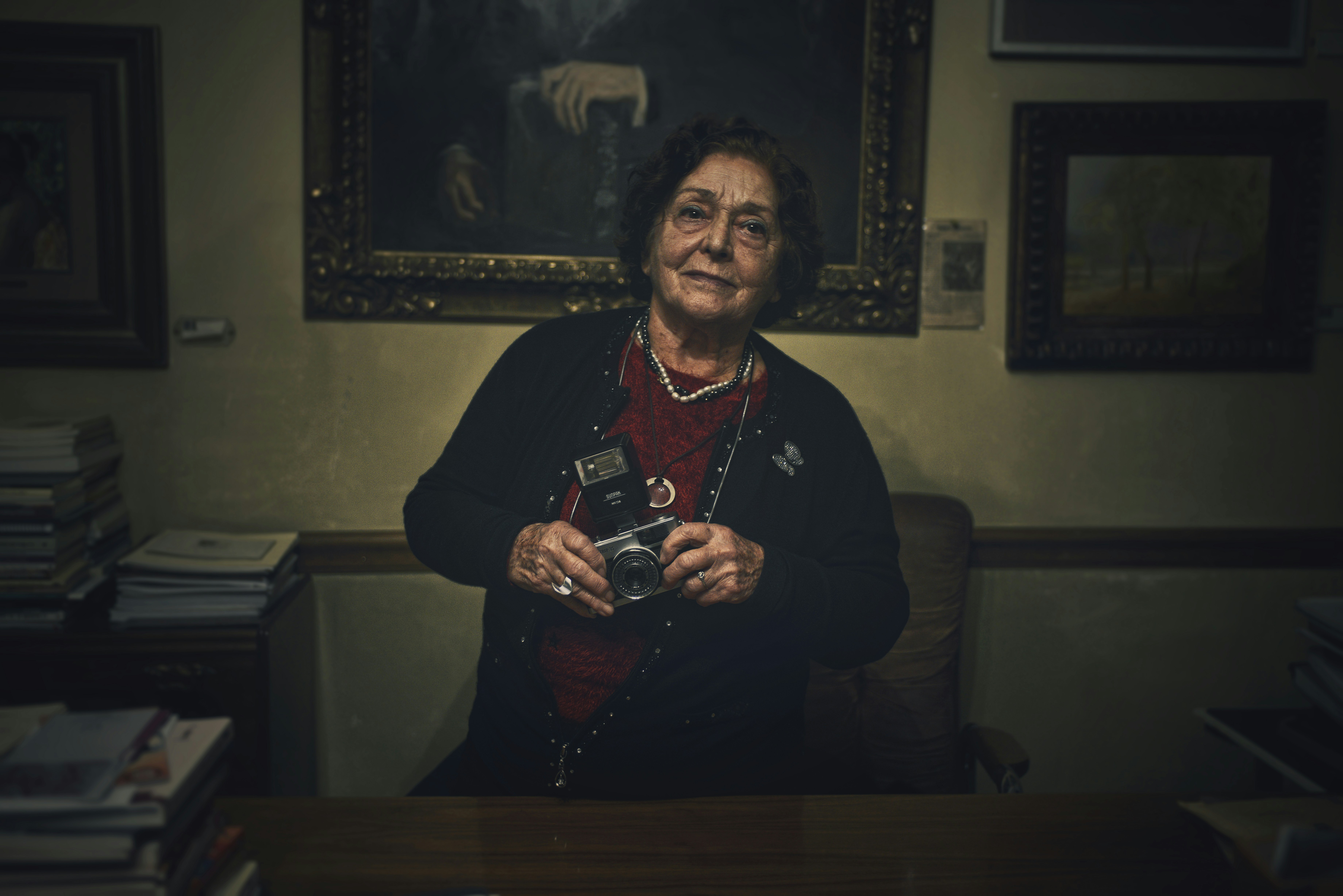 Elderly woman holding a vintage camera indoors