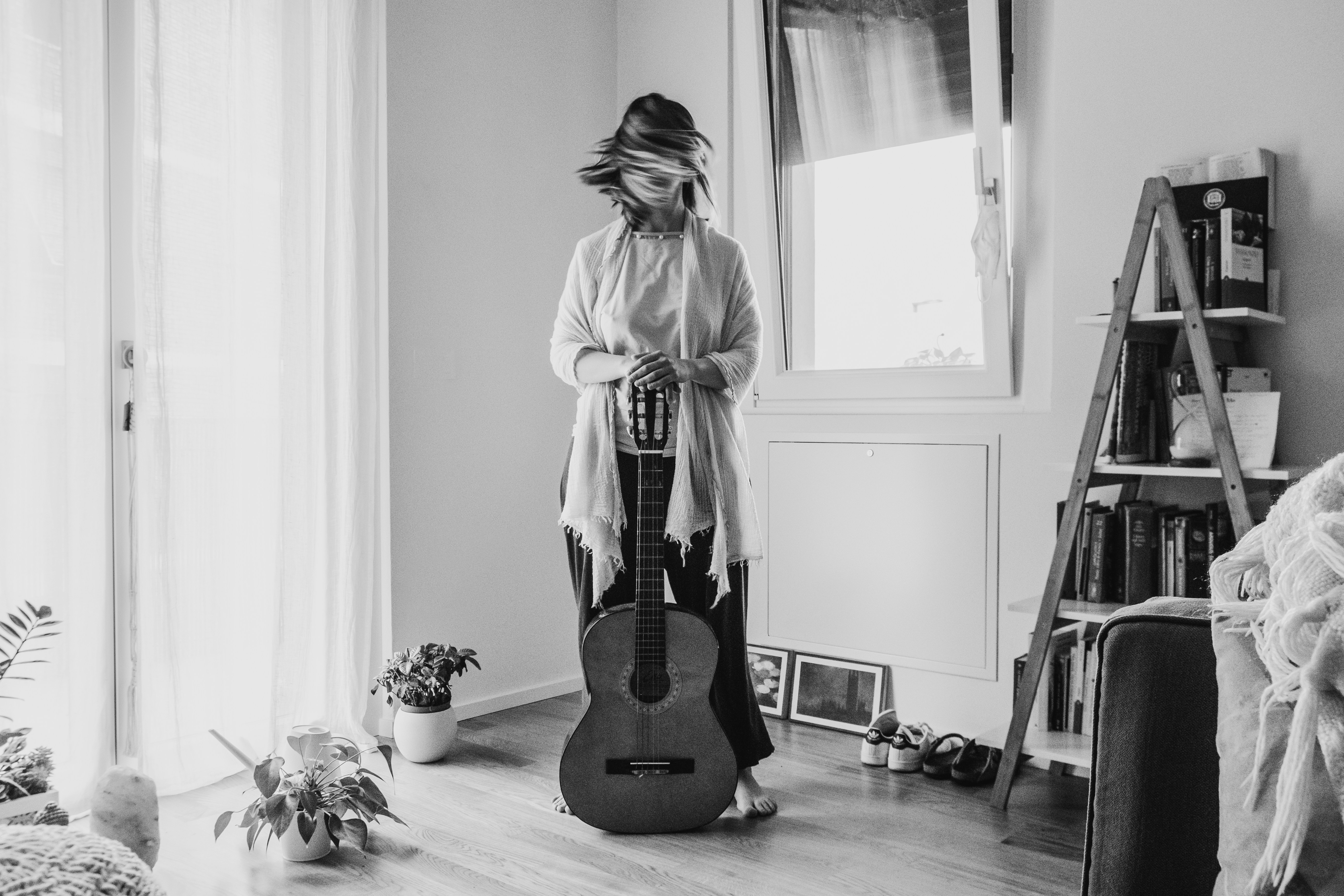 Woman with guitar standing indoors near window