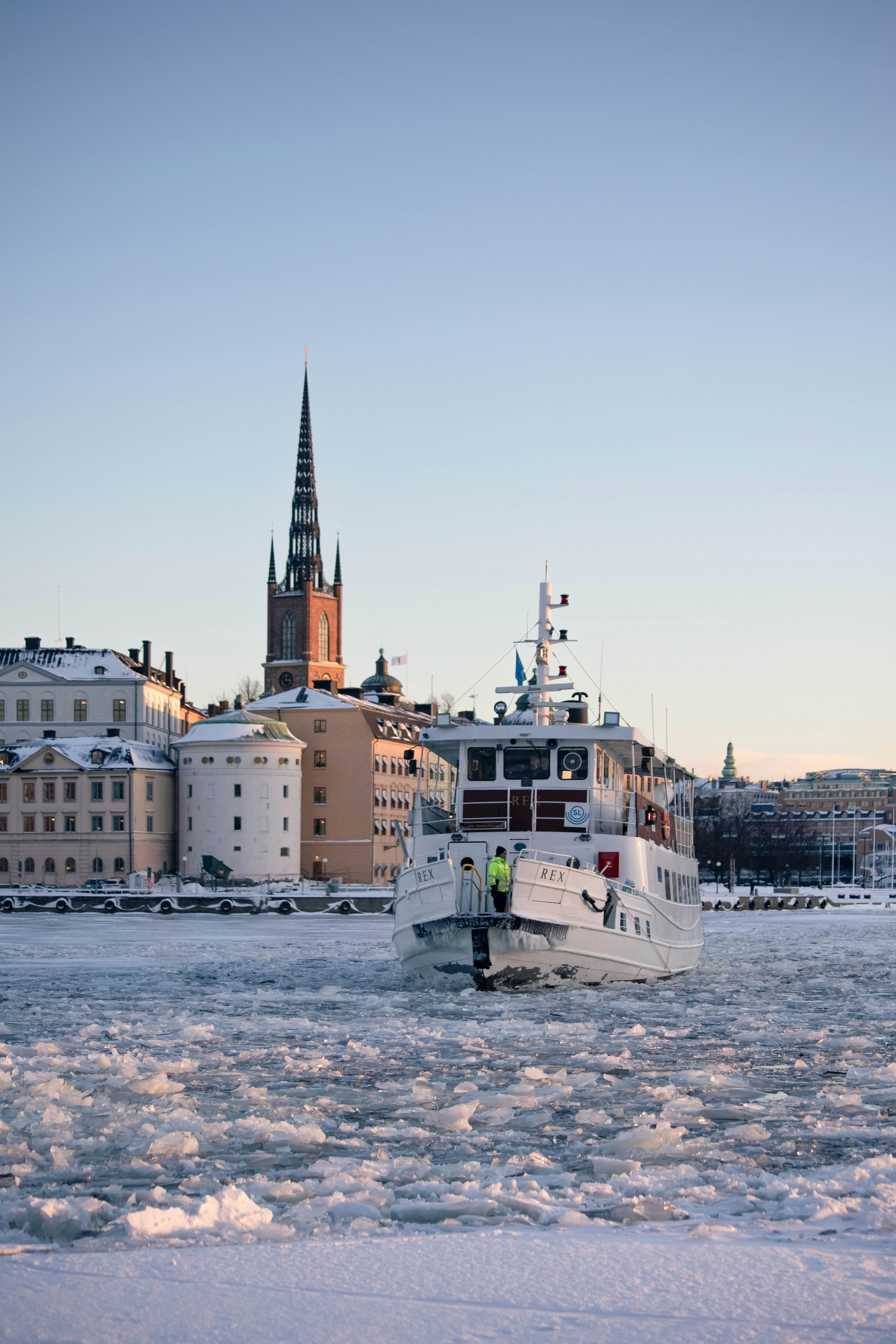 Ferry navigating icy waters in front of stockholm skyline.