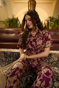 Woman in floral print outfit sits on patterned sofa