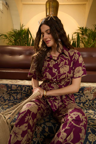 Woman in floral print outfit sits on patterned sofa