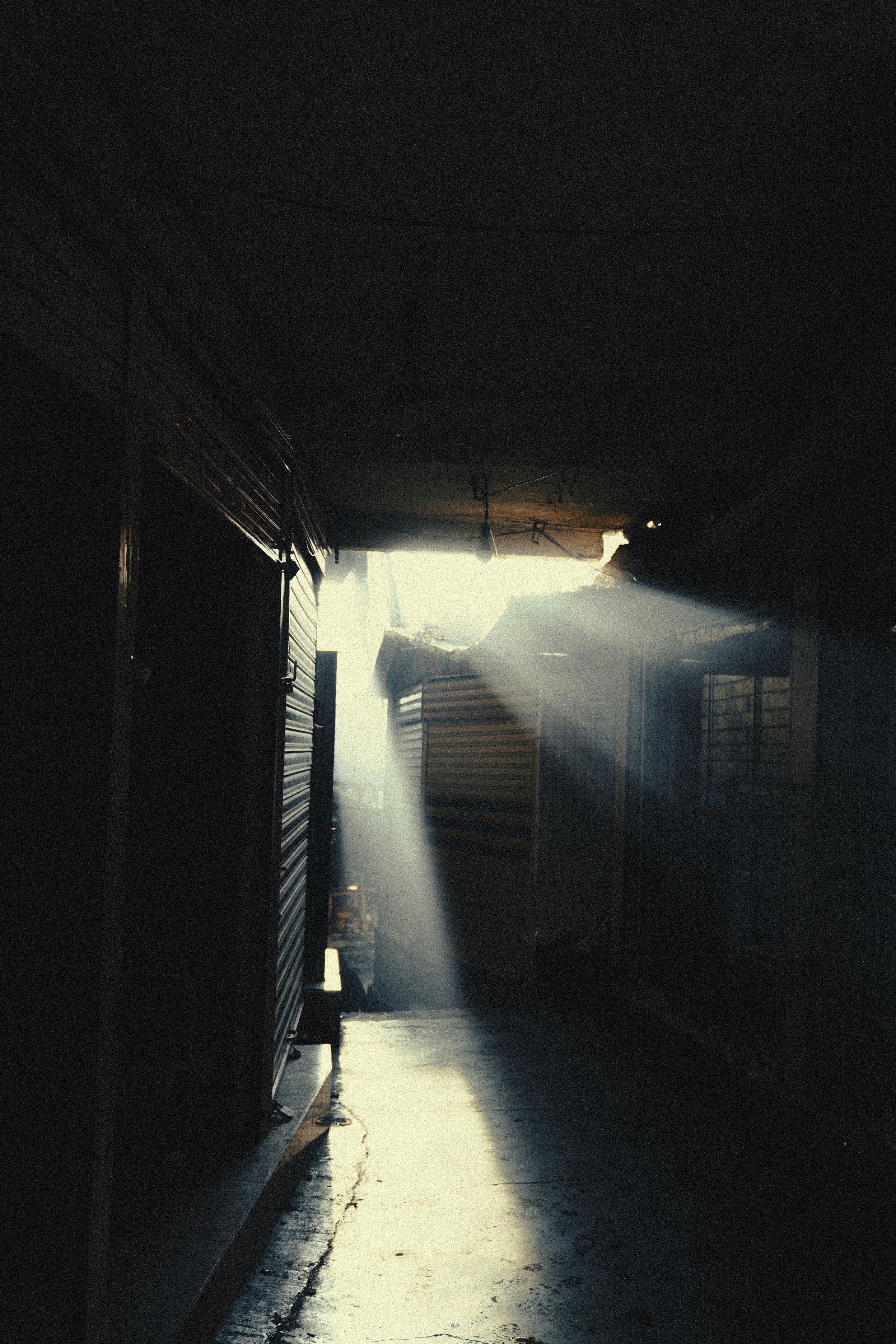 Sunlight streams through a dark, narrow alleyway.