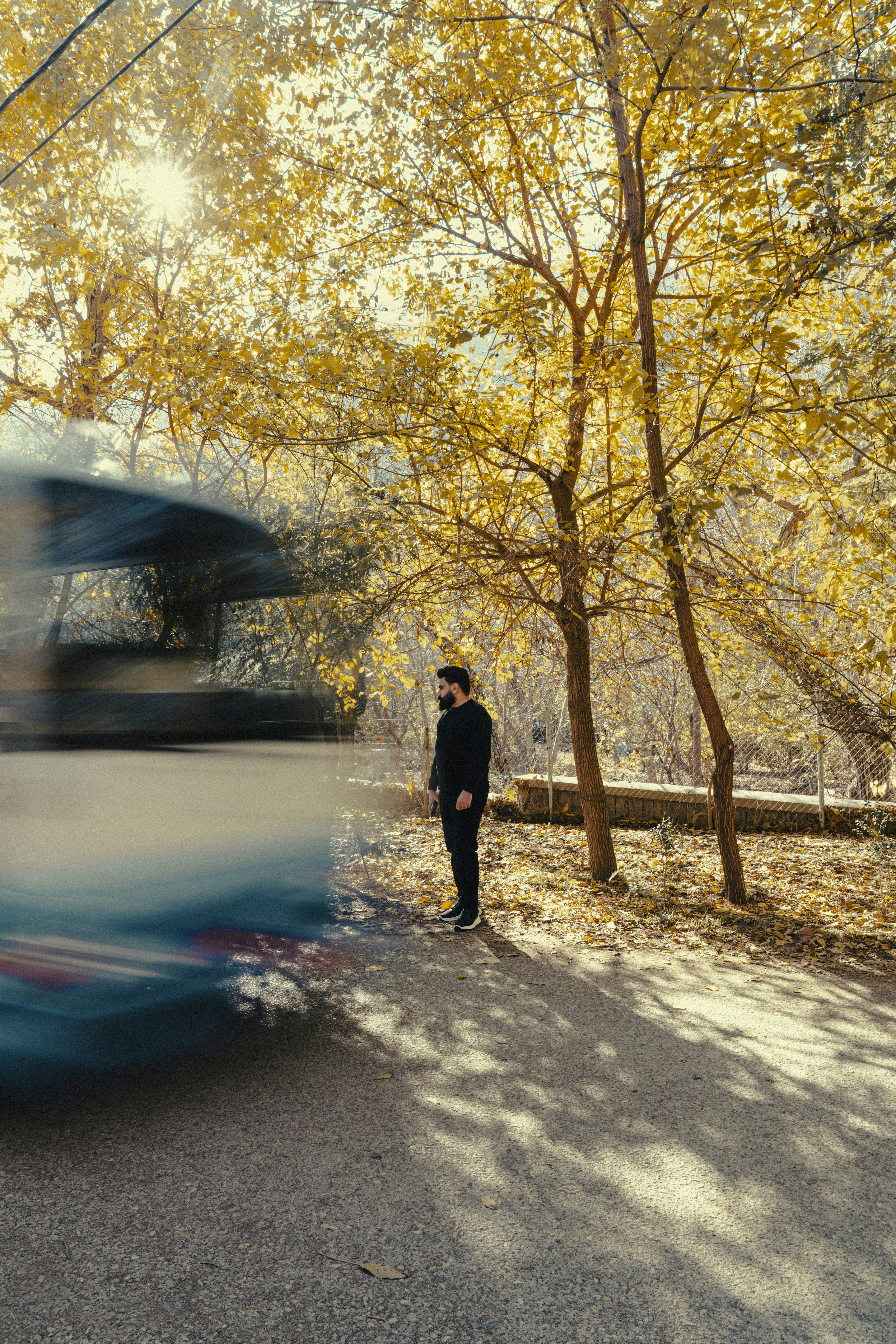 Man standing by road as bus passes.