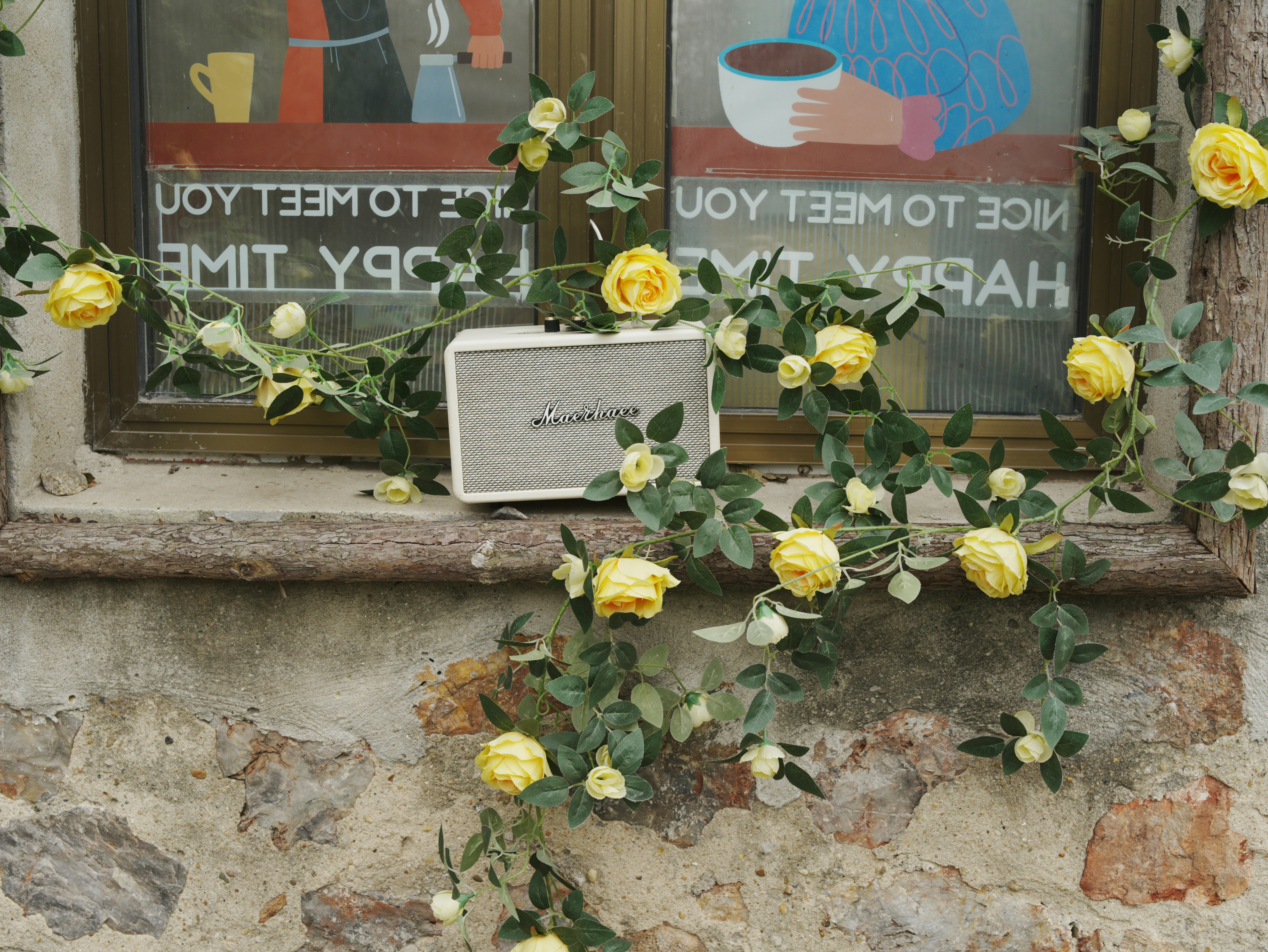 Yellow roses on a windowsill with a speaker.