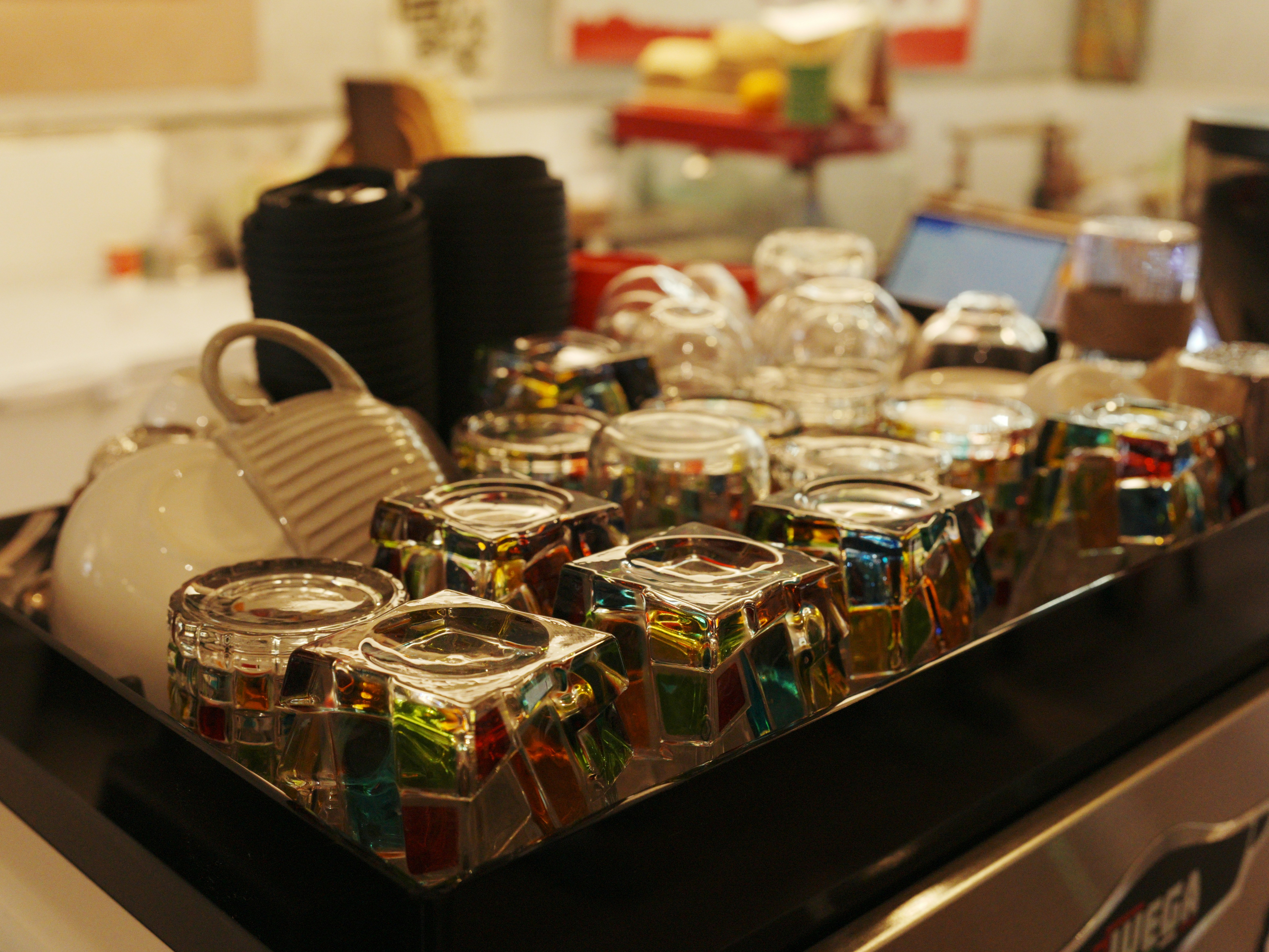 Row of colorful glass candle holders on tray
