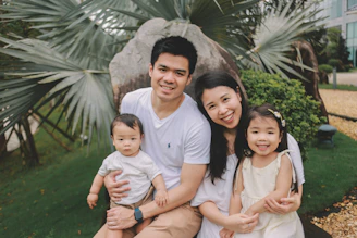 A family of four posing outdoors with palm trees.