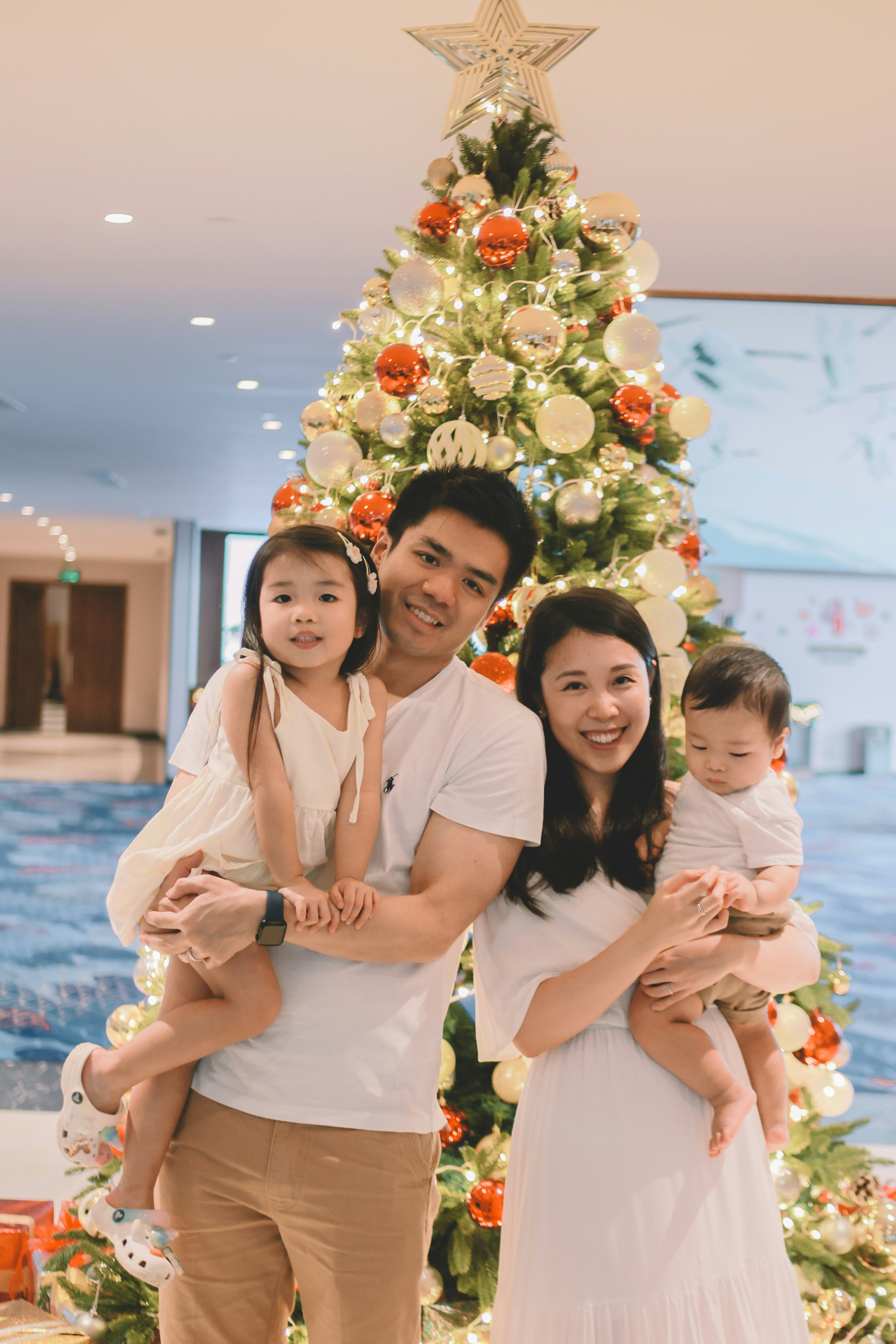 Family posing in front of a decorated christmas tree