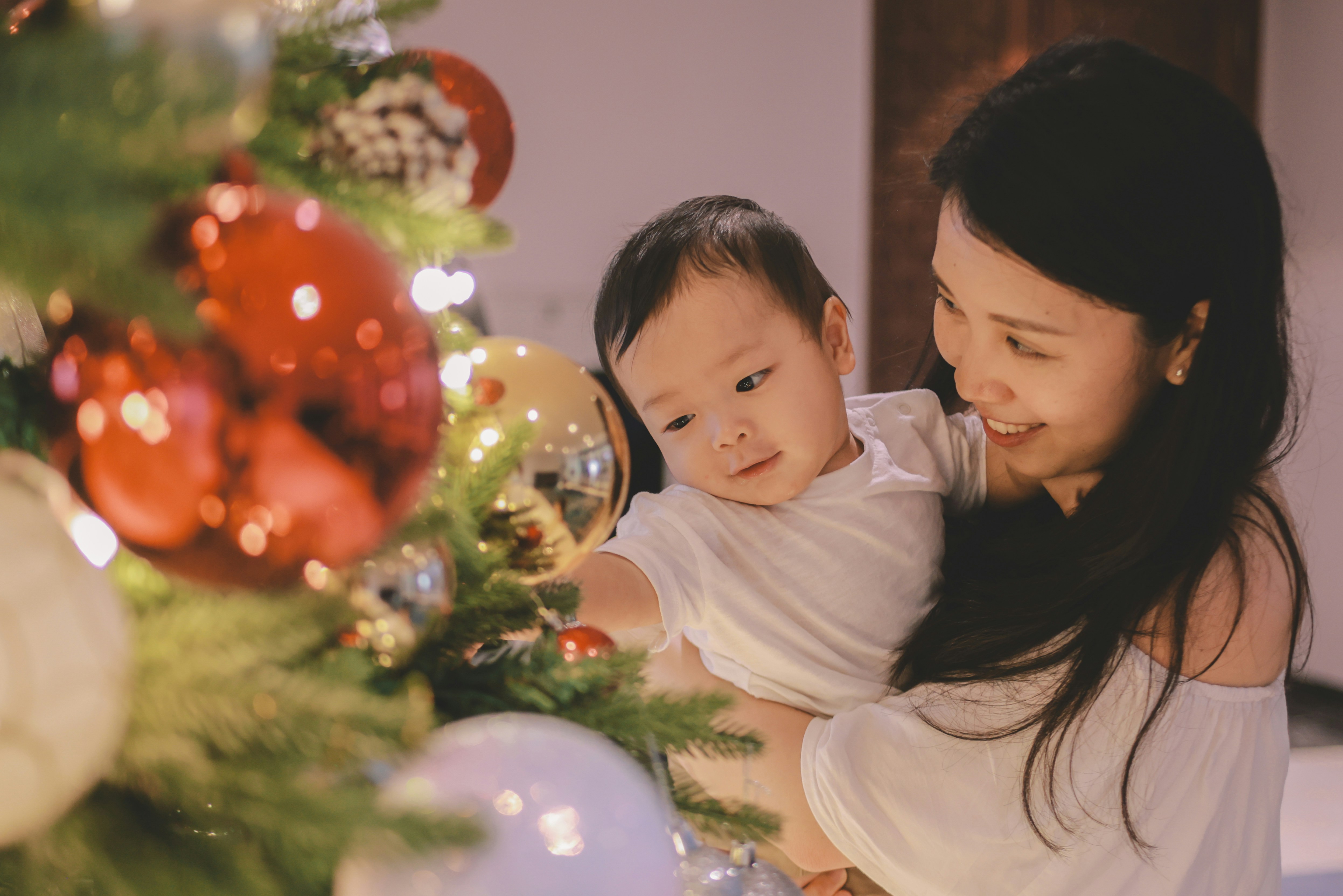 Mother and baby decorating christmas tree together
