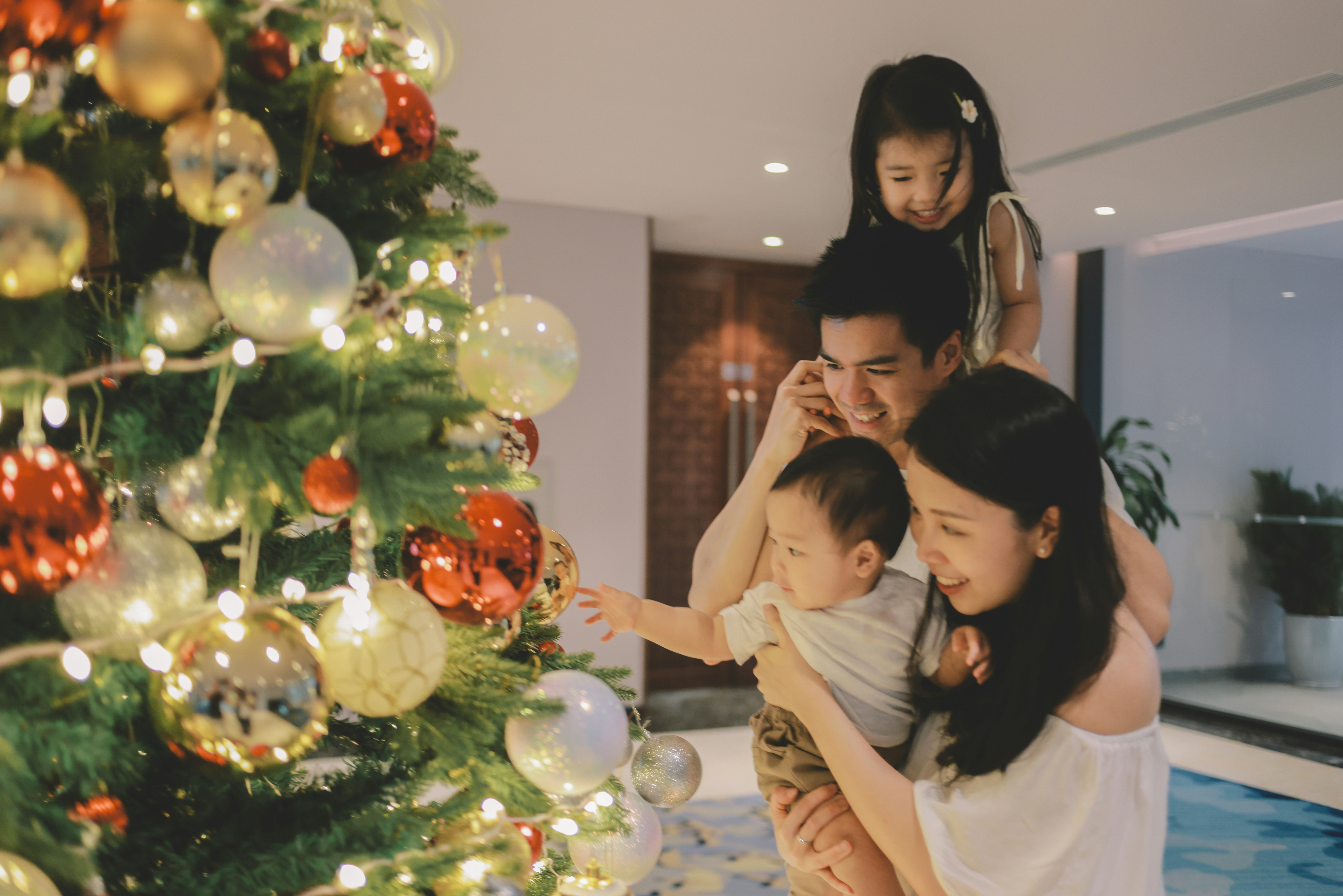 Family decorating a christmas tree with ornaments.