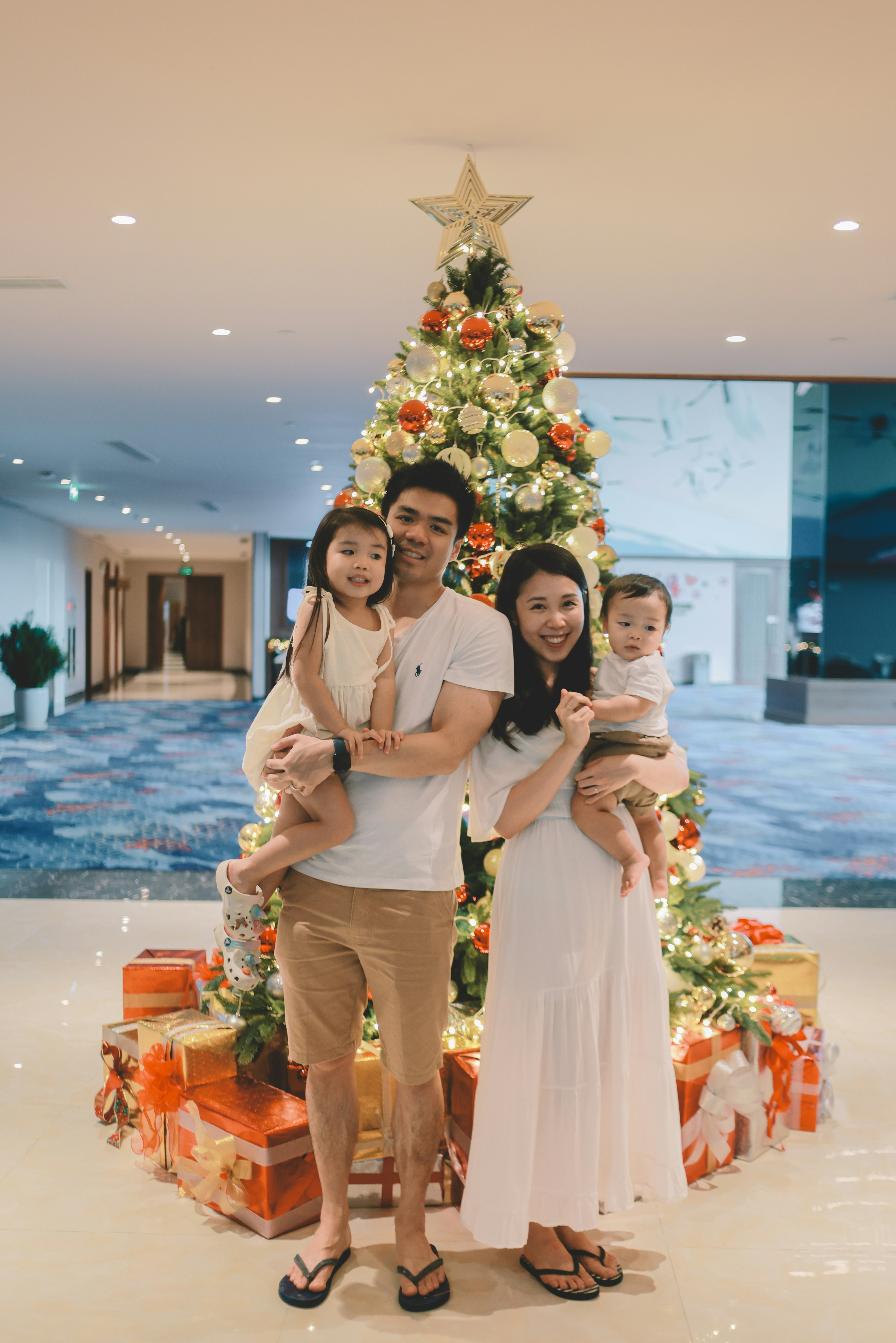 Family of four posing in front of a christmas tree.