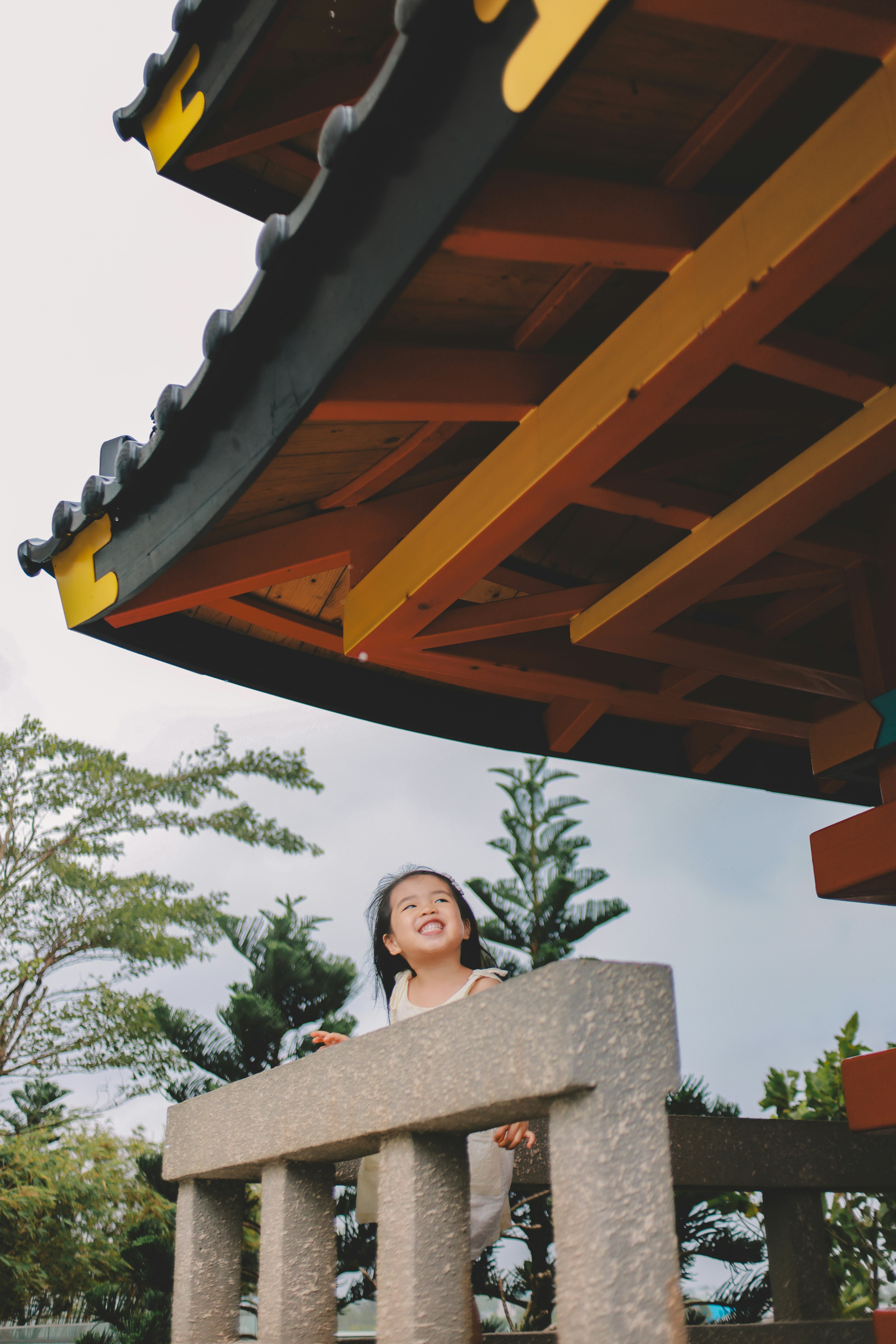 Uma garota sorridente sob um telhado ao estilo japonês