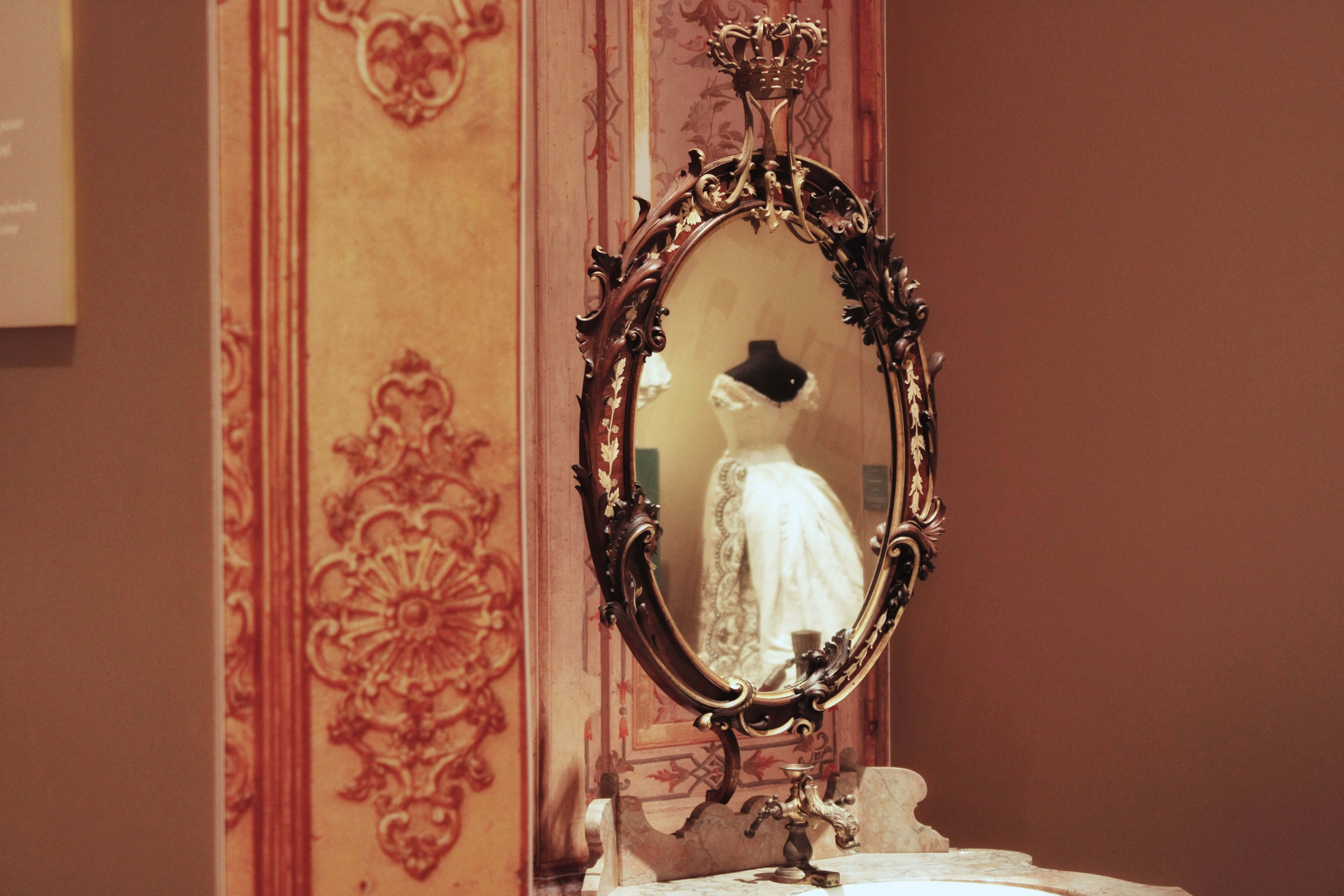 Ornate mirror reflects a vintage white dress.