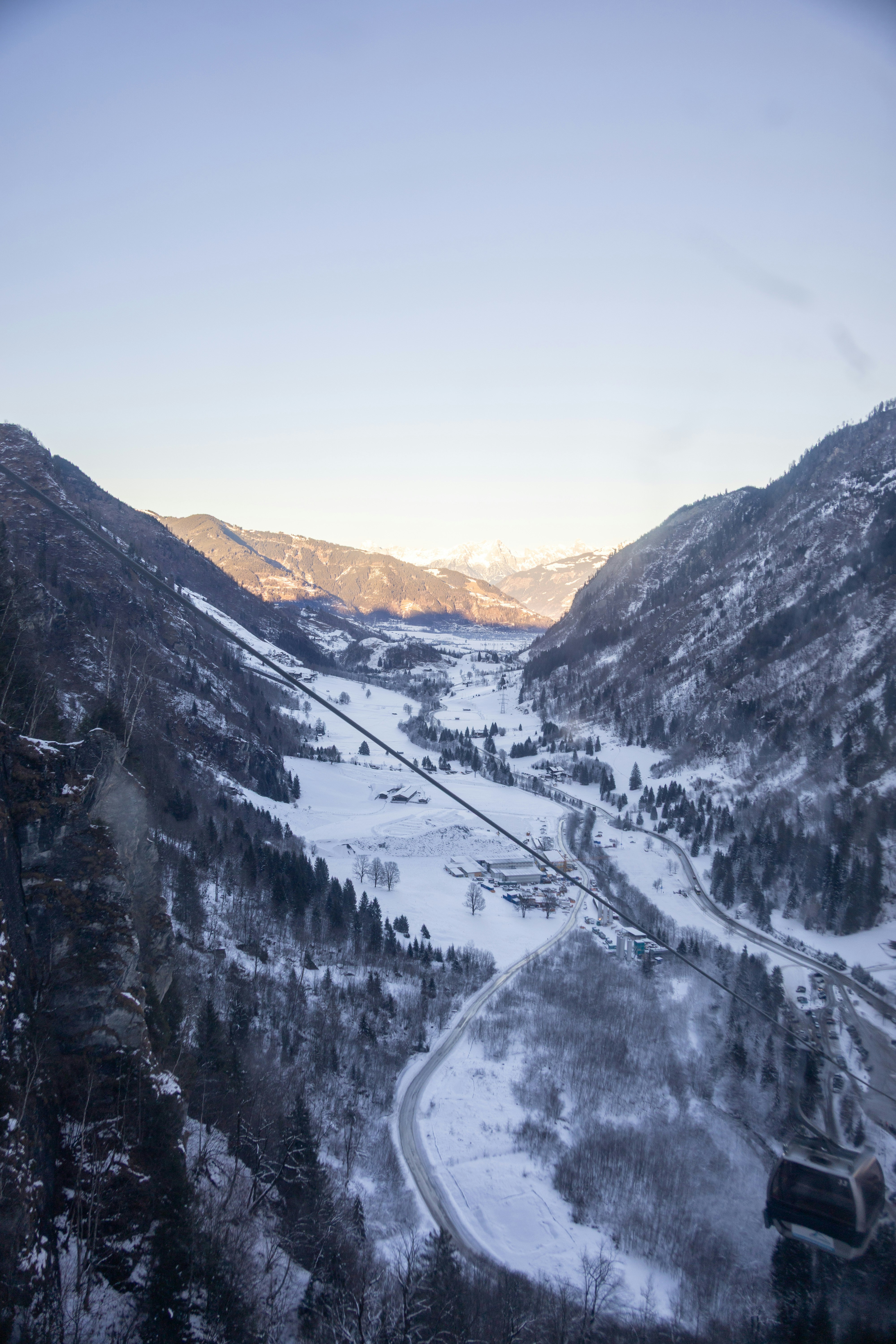 Valle nevado con montañas y un pueblo al atardecer
