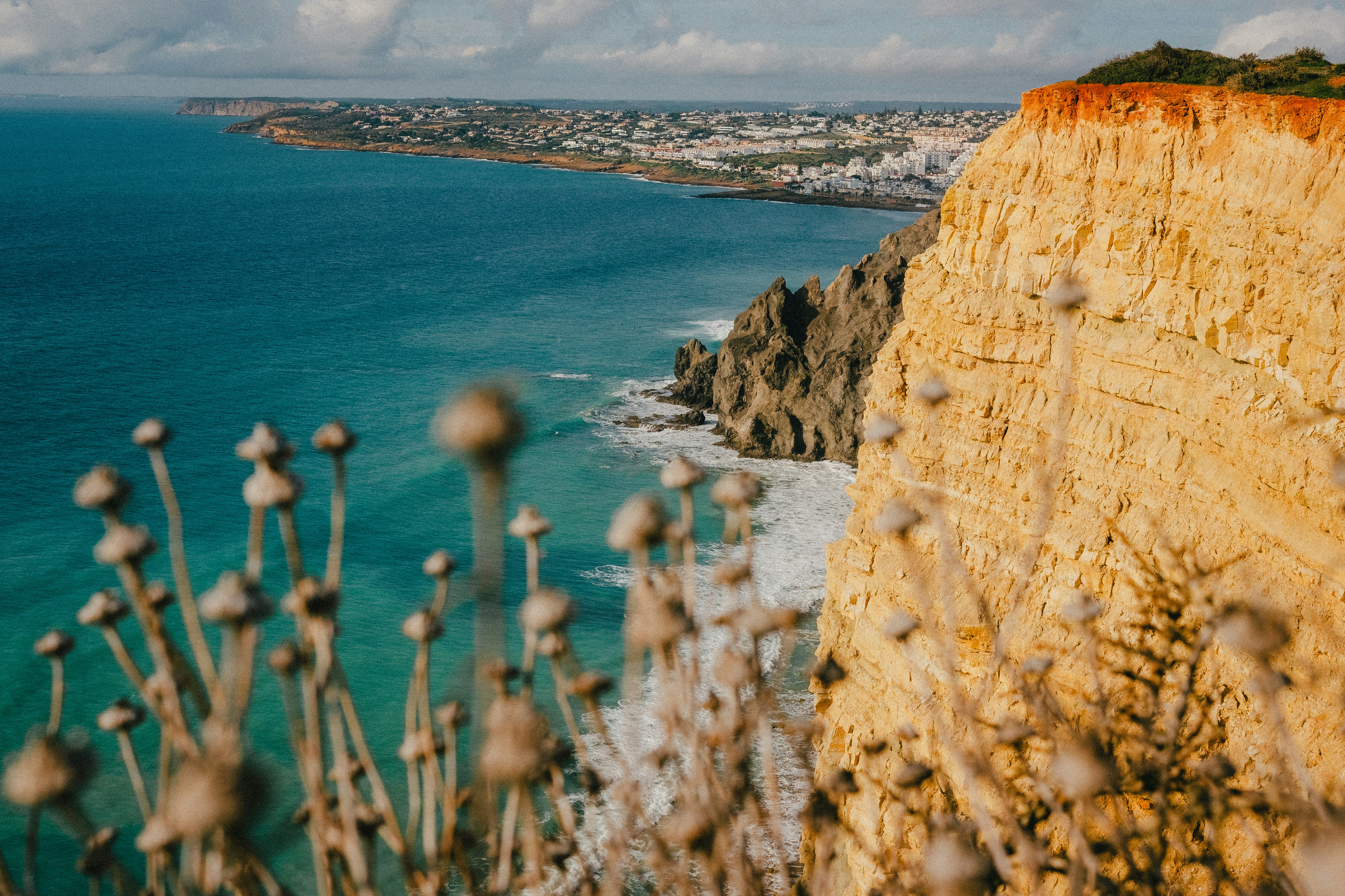 Coastal cliffs overlooking a blue ocean and town.