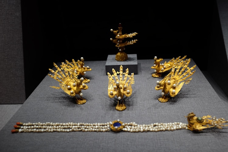 A collection of ornate golden jewelry adorned with gems, representing the tradition of temple offerings across Hindu and Buddhist faiths
