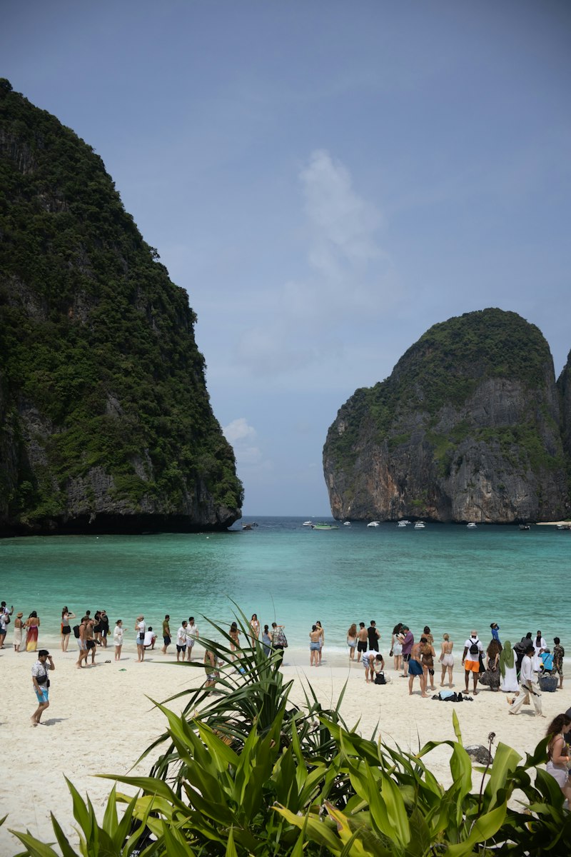 Tourists on a tropical beach with limestone cliffs in Thailand
