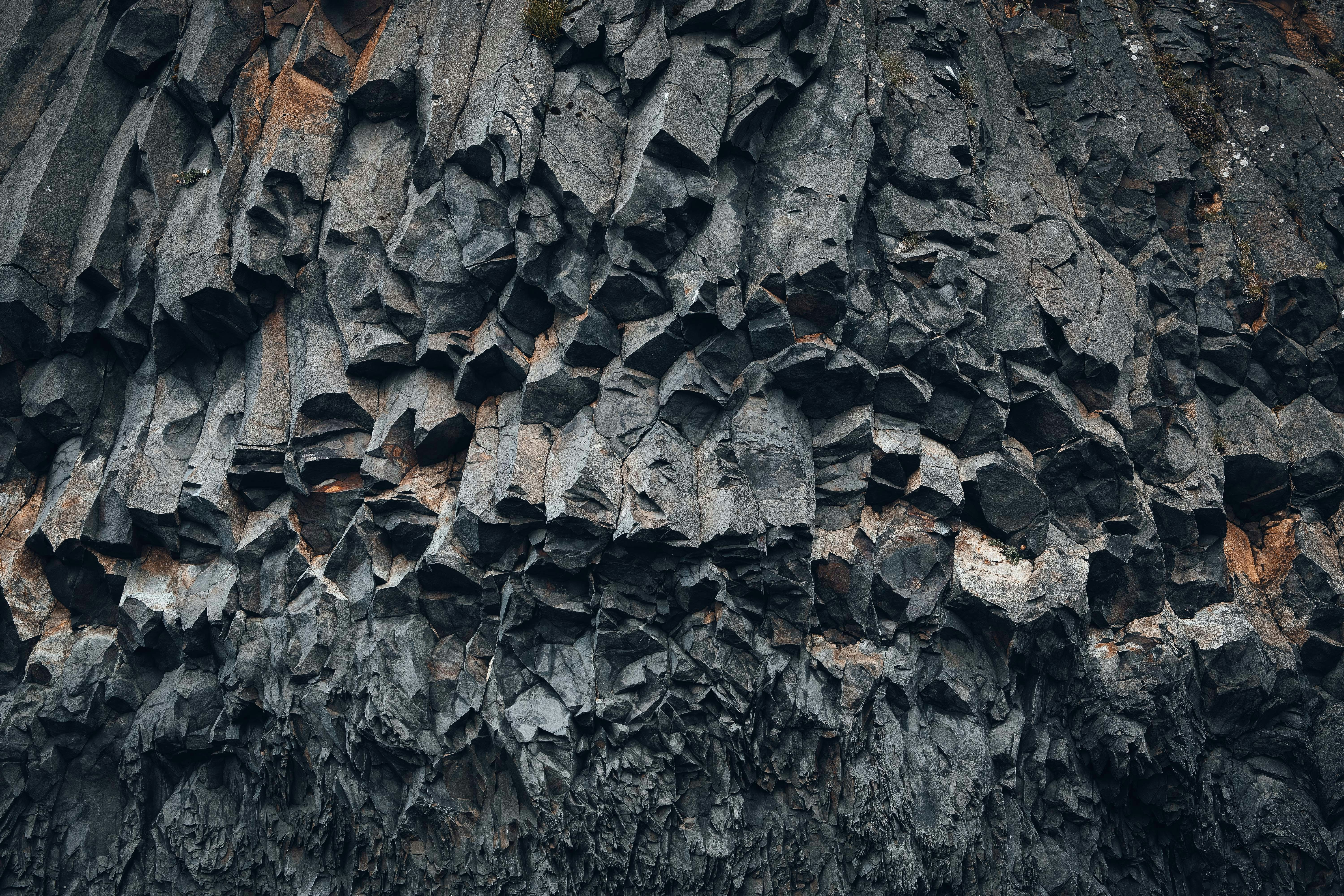 A close-up view of a dramatic basalt rock formation with natural geometric patterns. An abstract nature texture showcasing structure, repetition, and the raw power of volcanic landscapes.