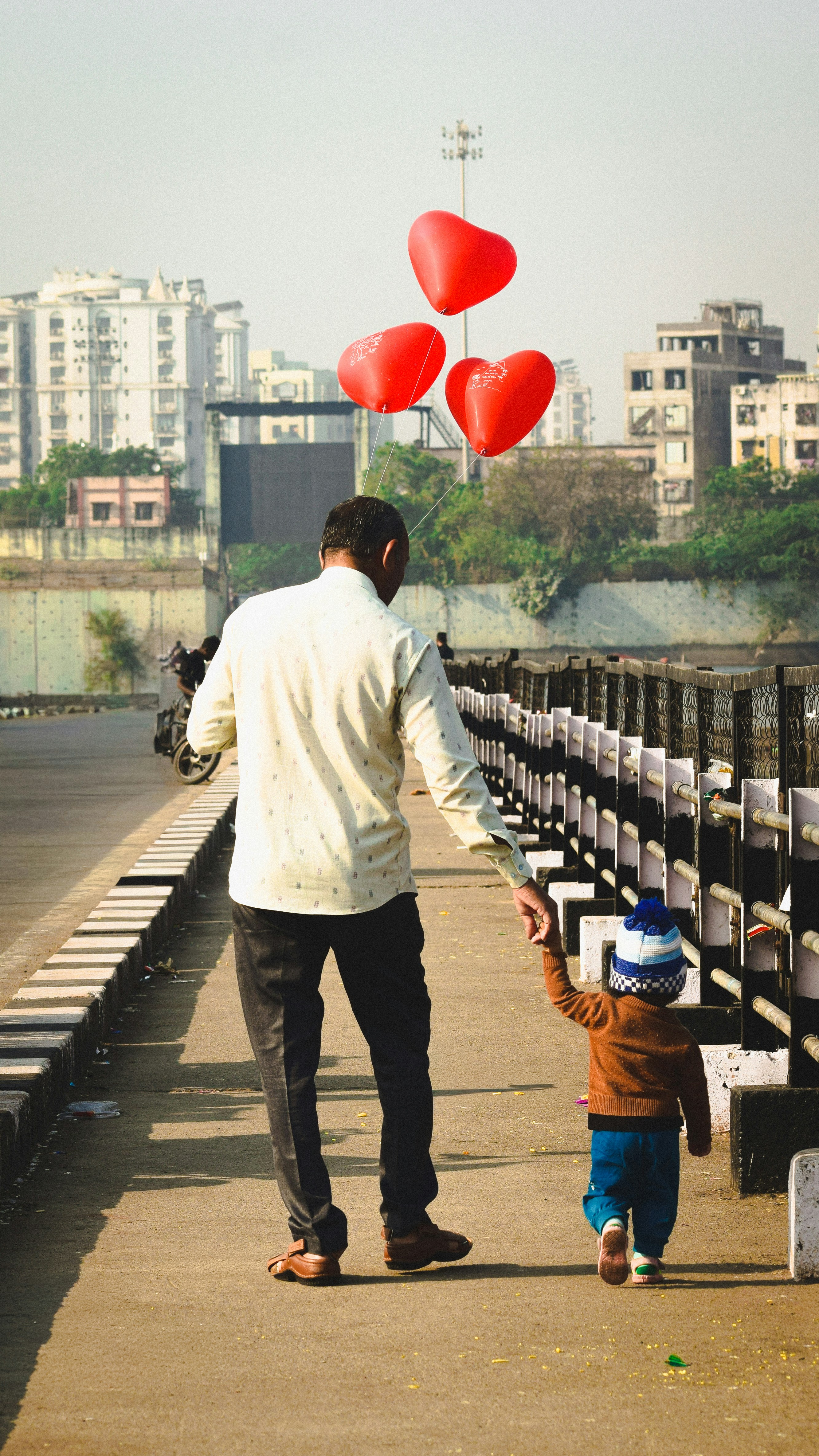 Father and child walking with red heart balloons