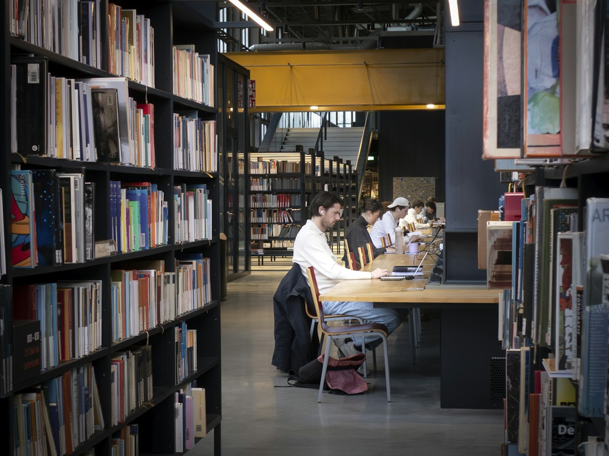 Students engaged in character education activities at tables in a modern library setting.