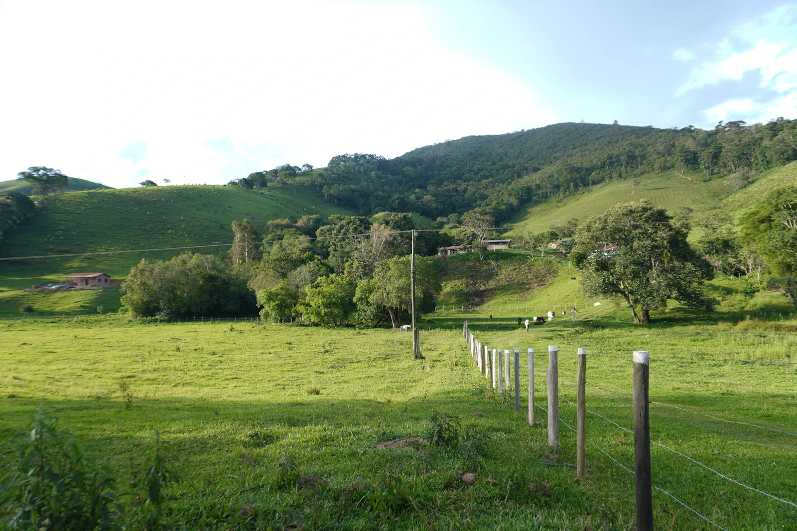 Casa rural com cerca de madeira em colinas verdes característica do interior do Brasil