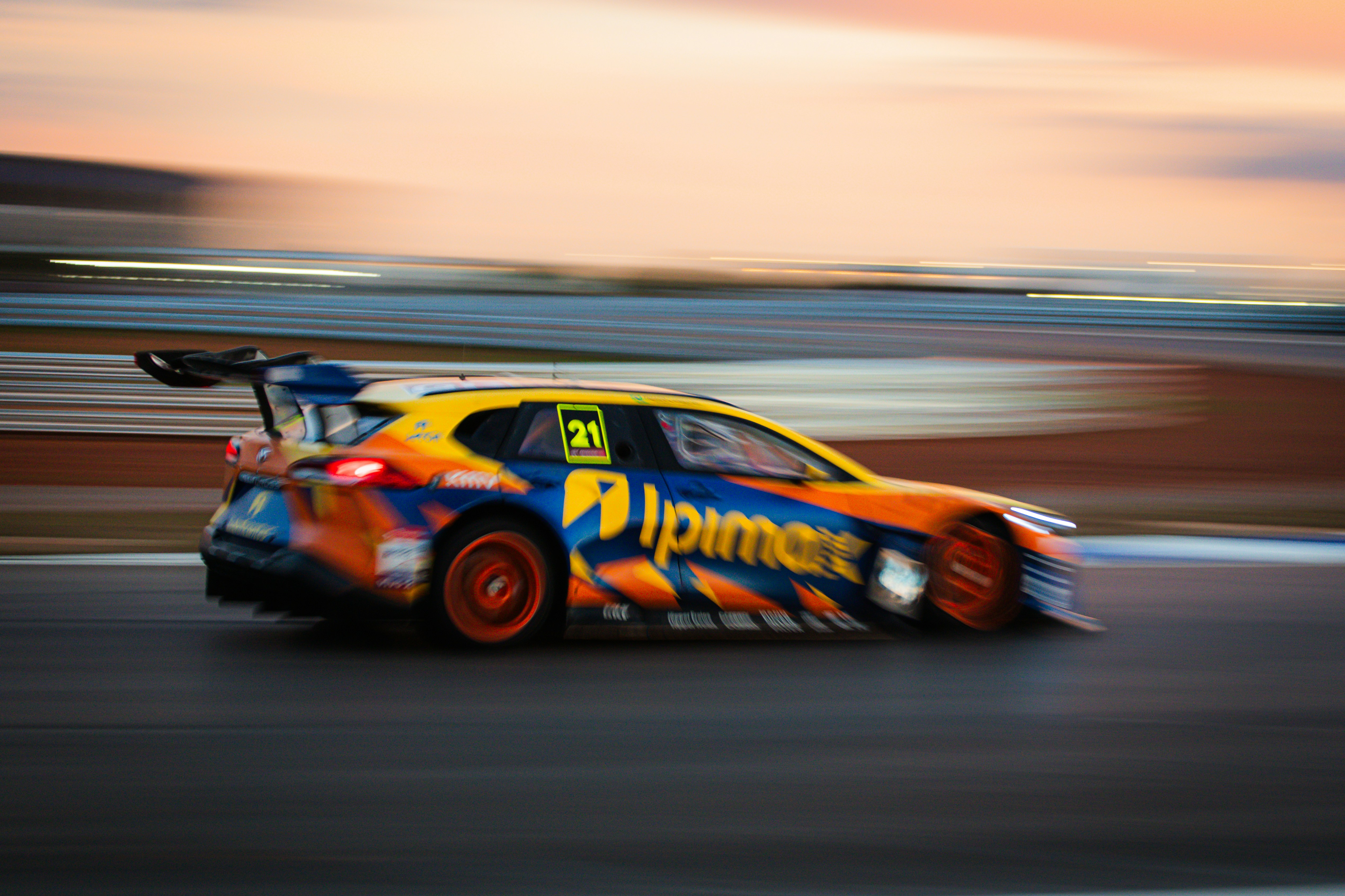 Race car speeding down track at sunset.