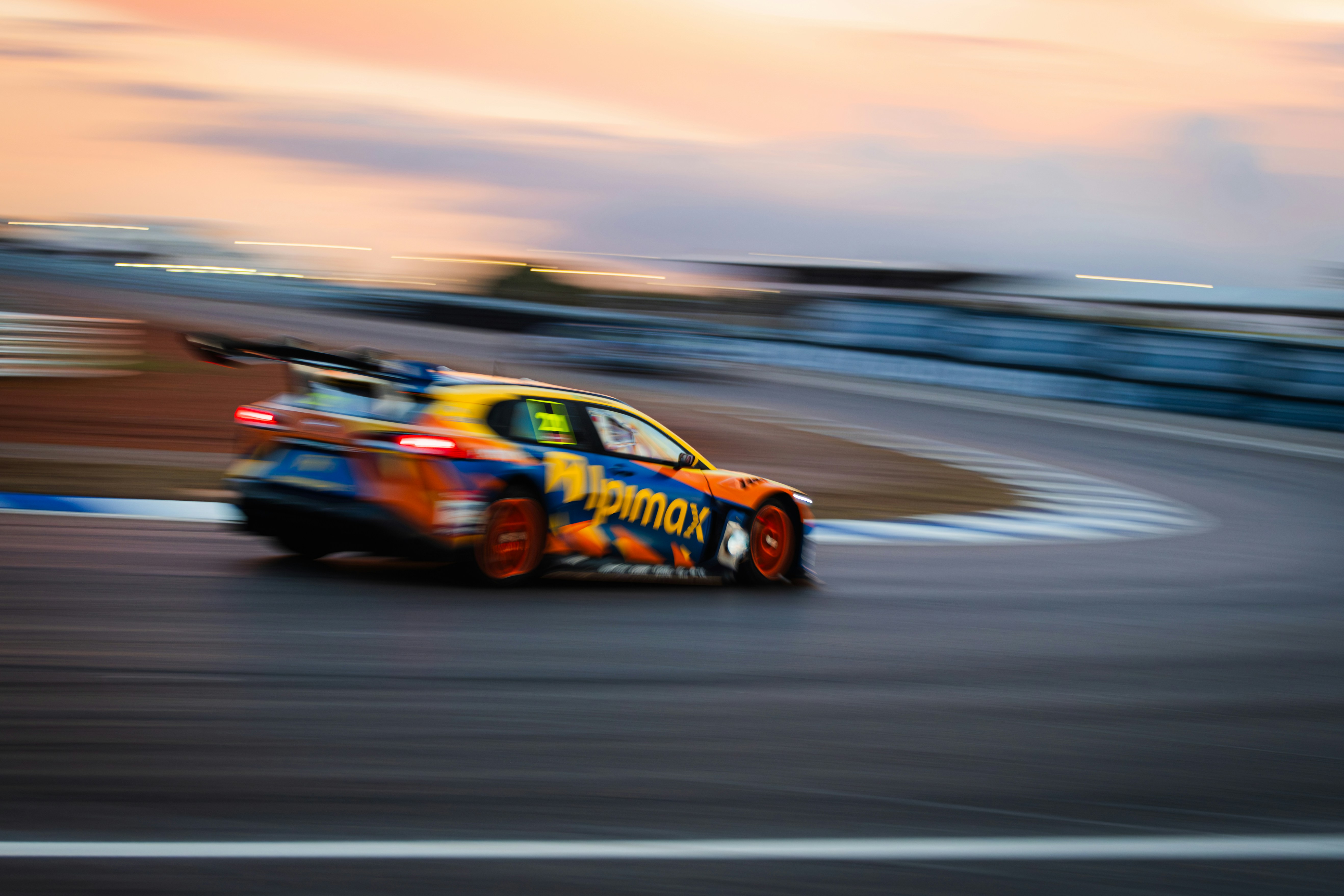 Race car speeding around a track at sunset