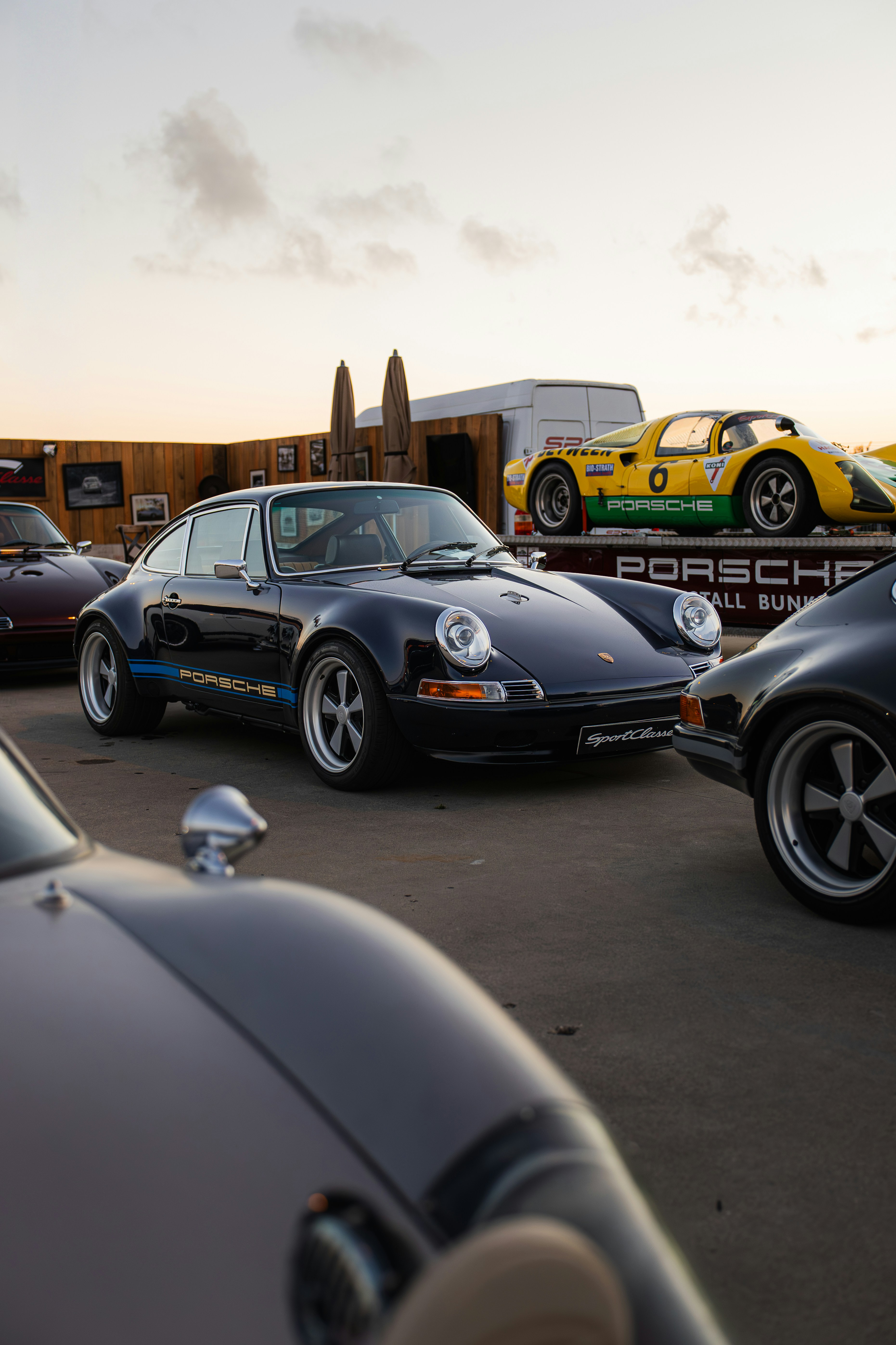 Several vintage porsche cars displayed outdoors at sunset.