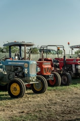 Three vintage tractors parked outdoors on a sunny day.
