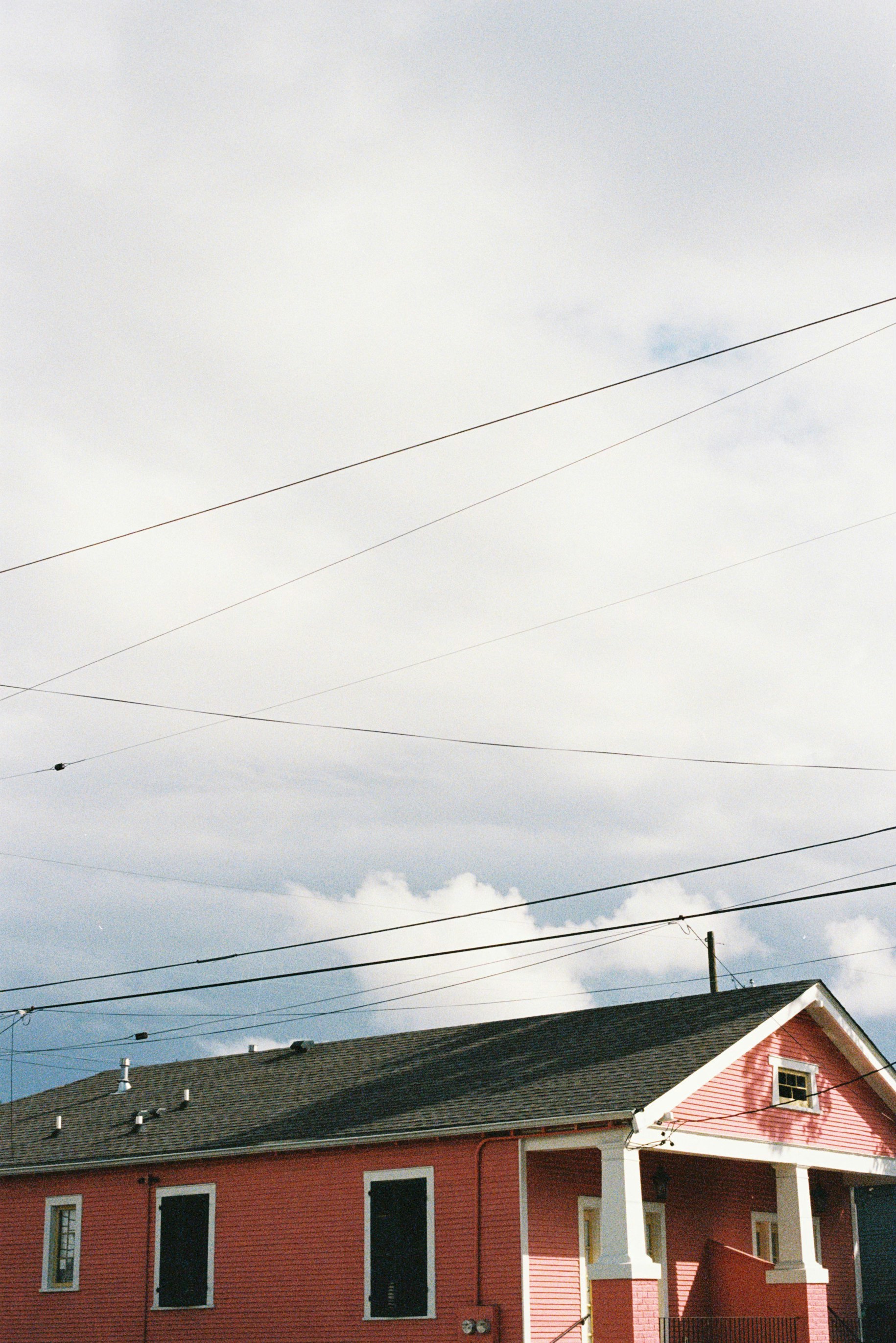 Red house with dark windows under cloudy sky.