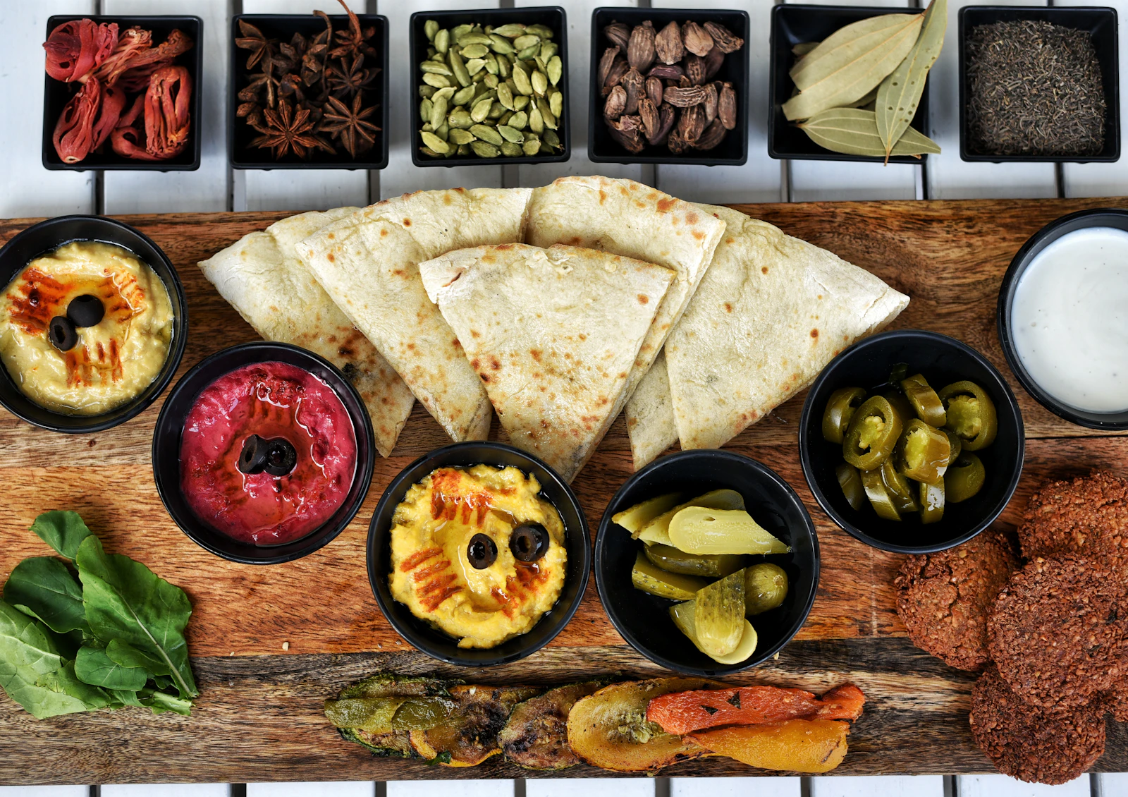 Illustrative image for vegan food in cairo: ful, taameya and koshari: A broad table of flatbread, falafel, dips, vegetables, pickles and spices.