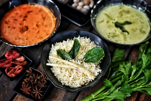 Three bowls of indian food with rice and spices