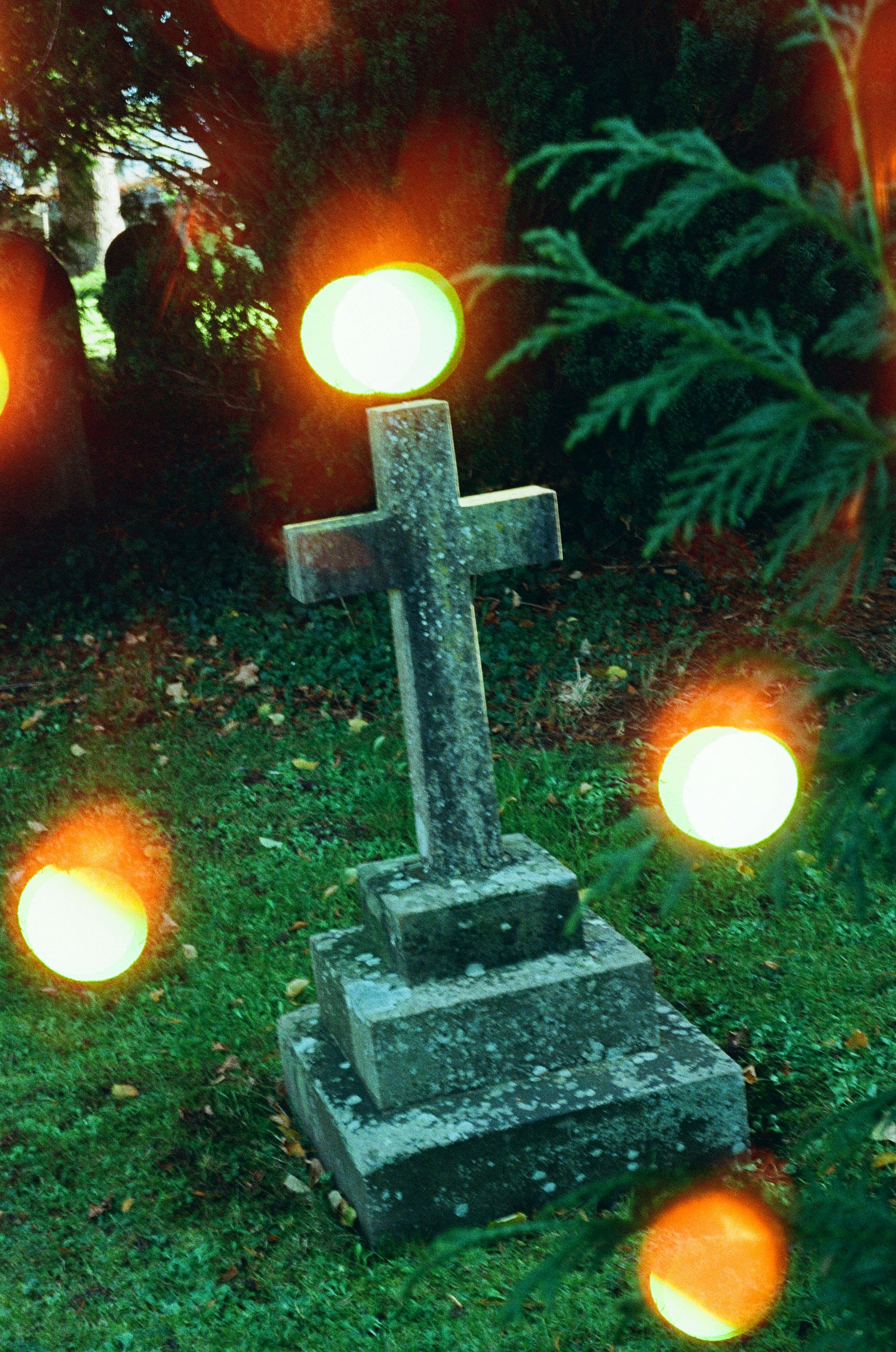 Lápide de cruz de pedra em um cemitério gramado