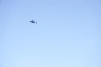 A helicopter flies in the clear blue sky.