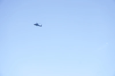 A helicopter flies in the clear blue sky.