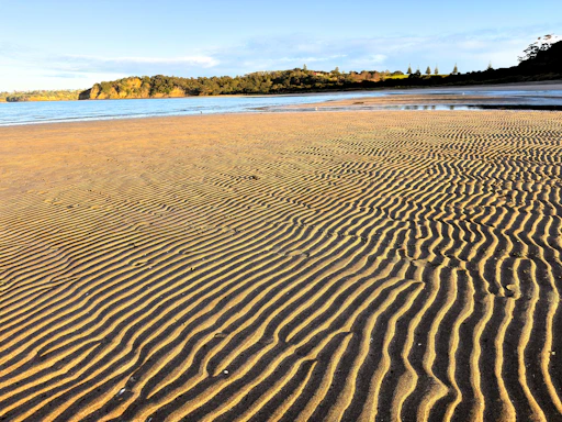 Rippled sand on a beach with calm water.