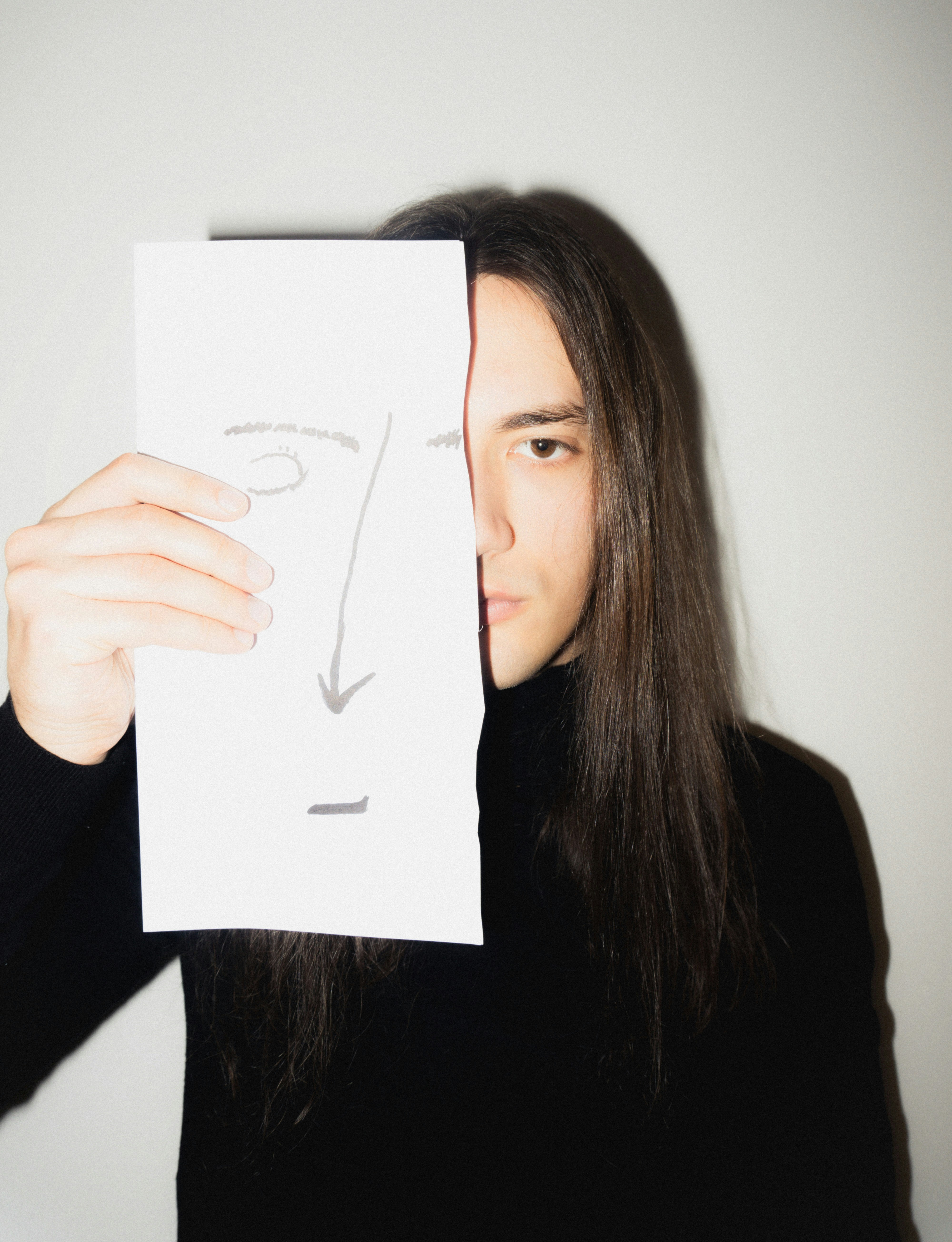 Man holding drawing of face over his face