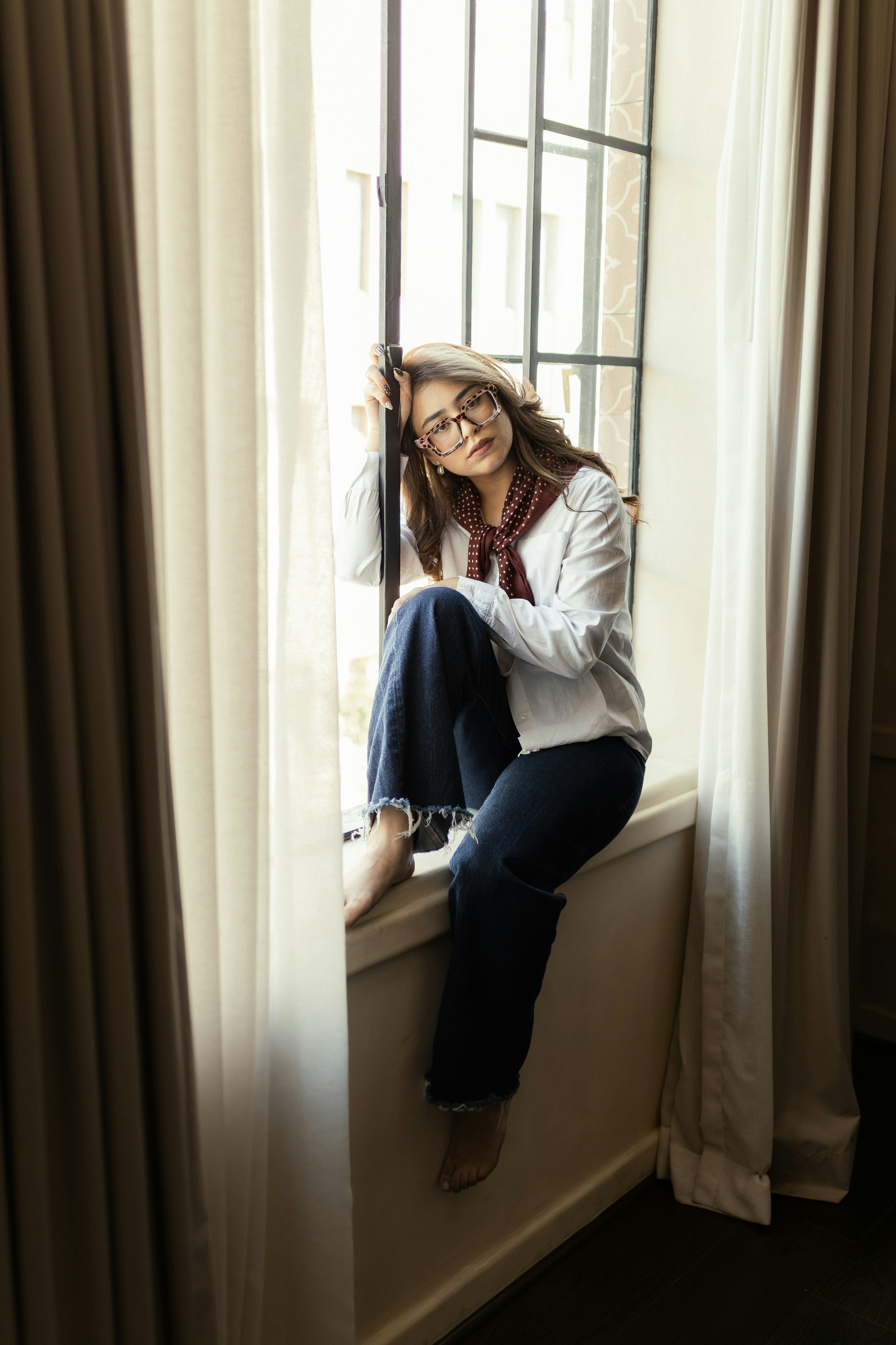 Woman sitting on a windowsill looking thoughtful