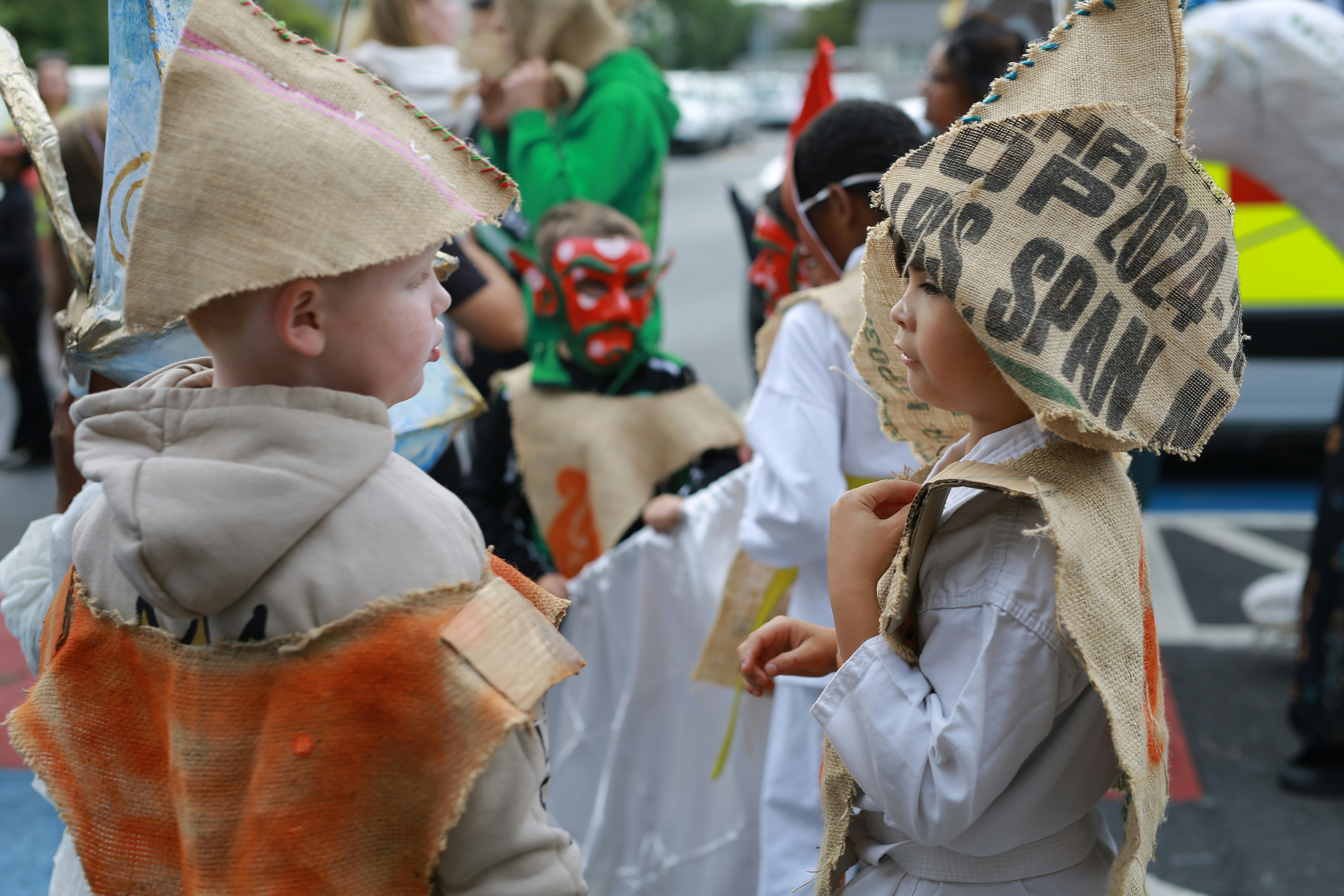 Children in burlap hats and costumes at a parade.
